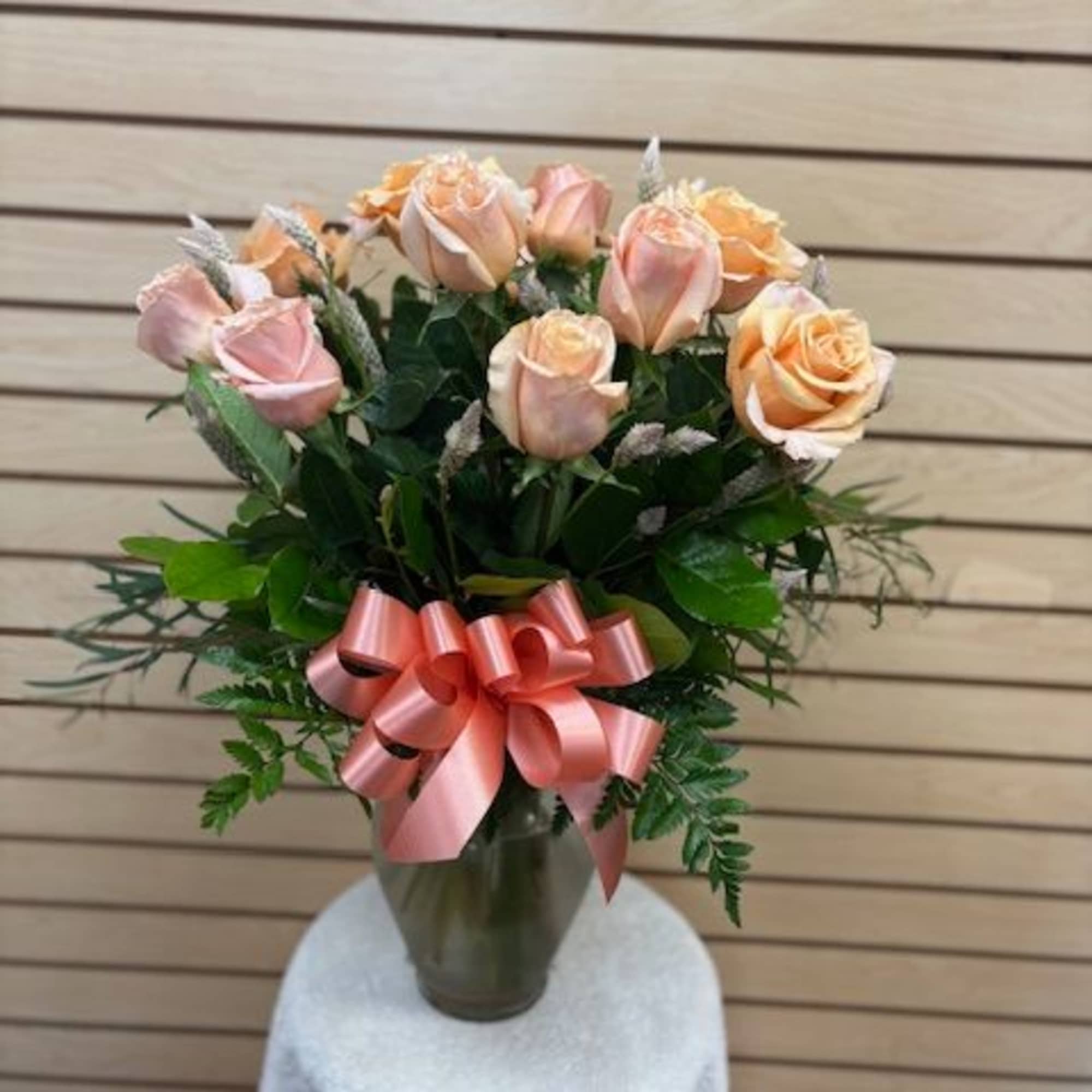 Pink and peach roses in a glass vase with a pink ribbon bow