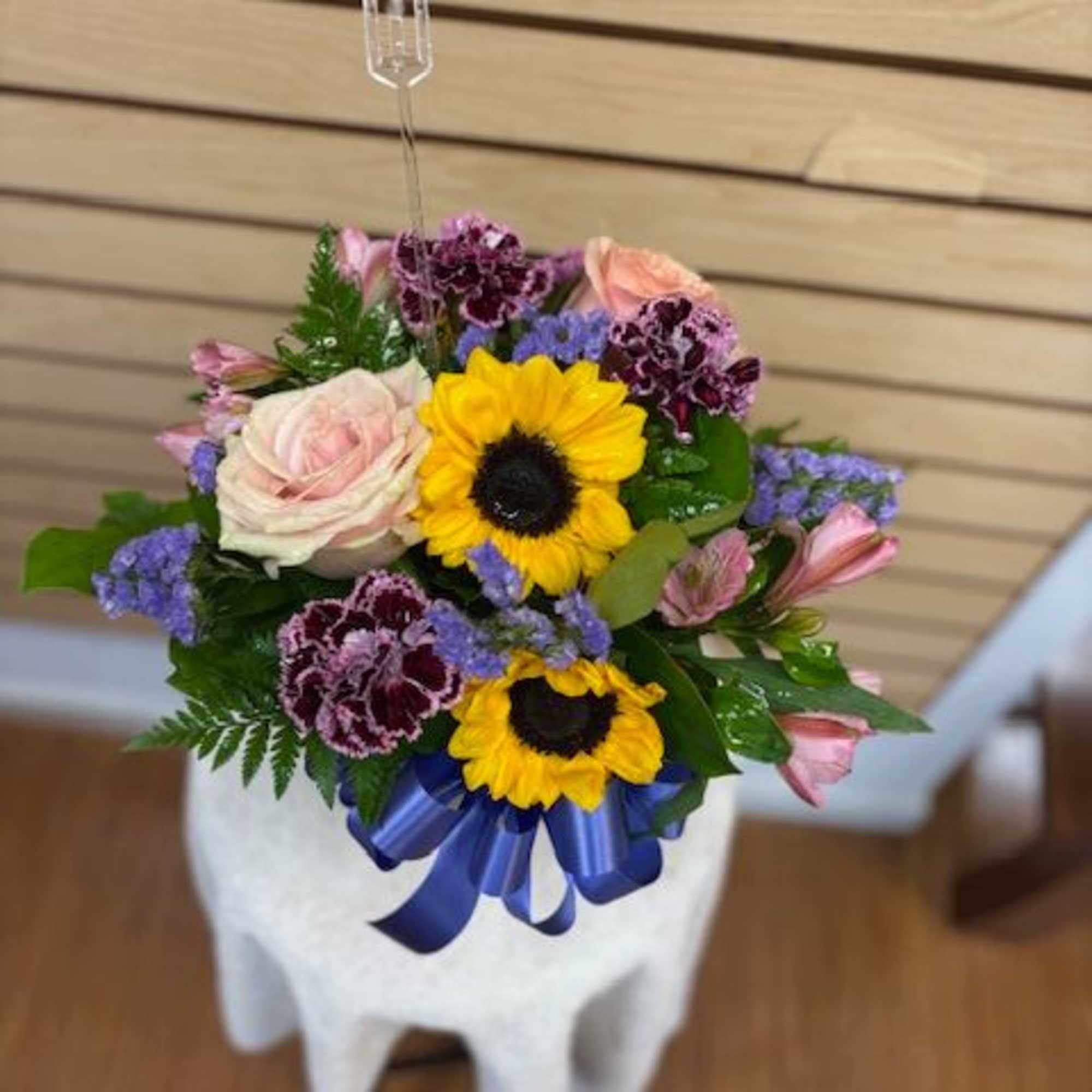Mixed bouquet with sunflowers, roses, and carnations in a white vase