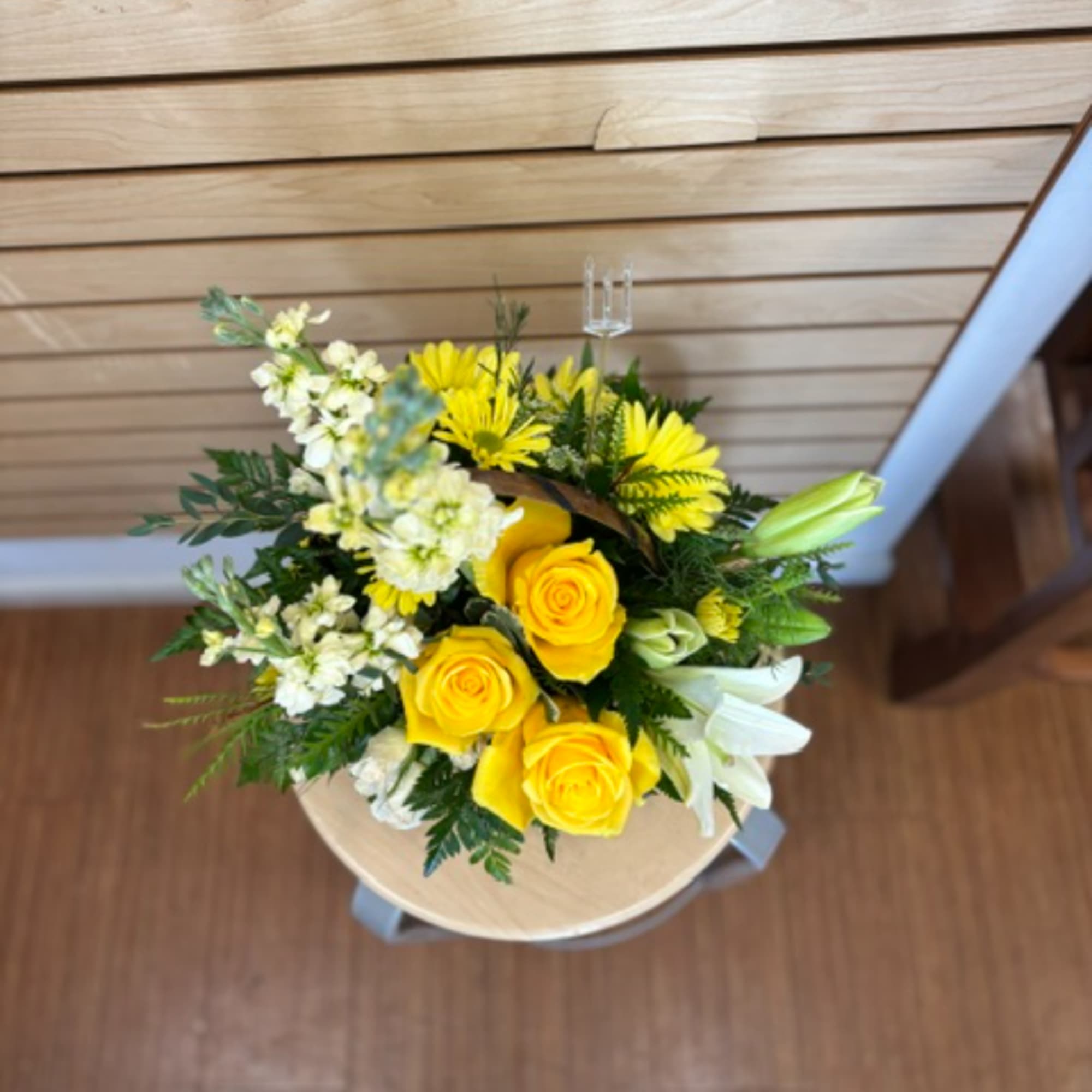 Yellow roses and white lilies arranged in a round bouquet