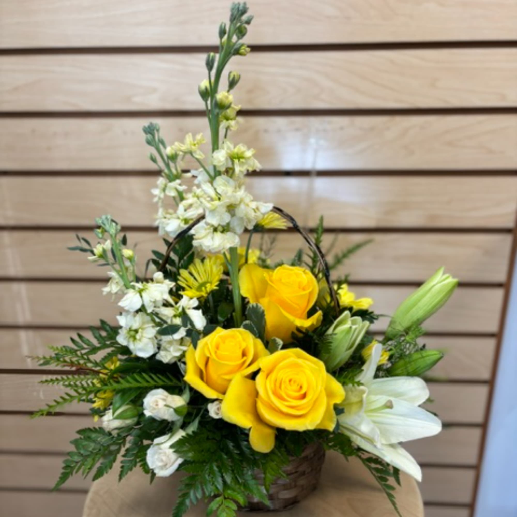 Yellow roses and white lilies arranged in a basket