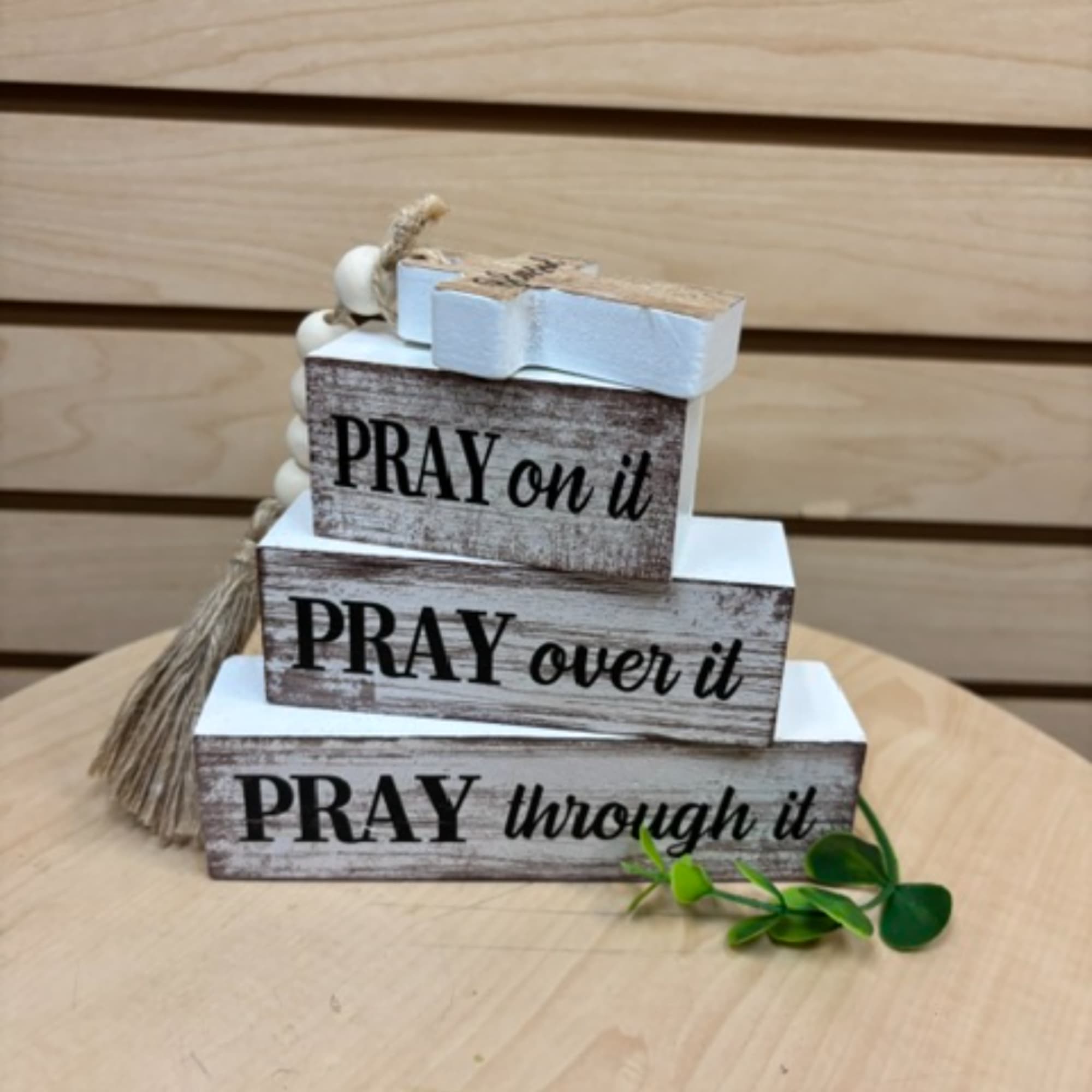 Stacked wooden blocks with prayer phrases and small decorative accents