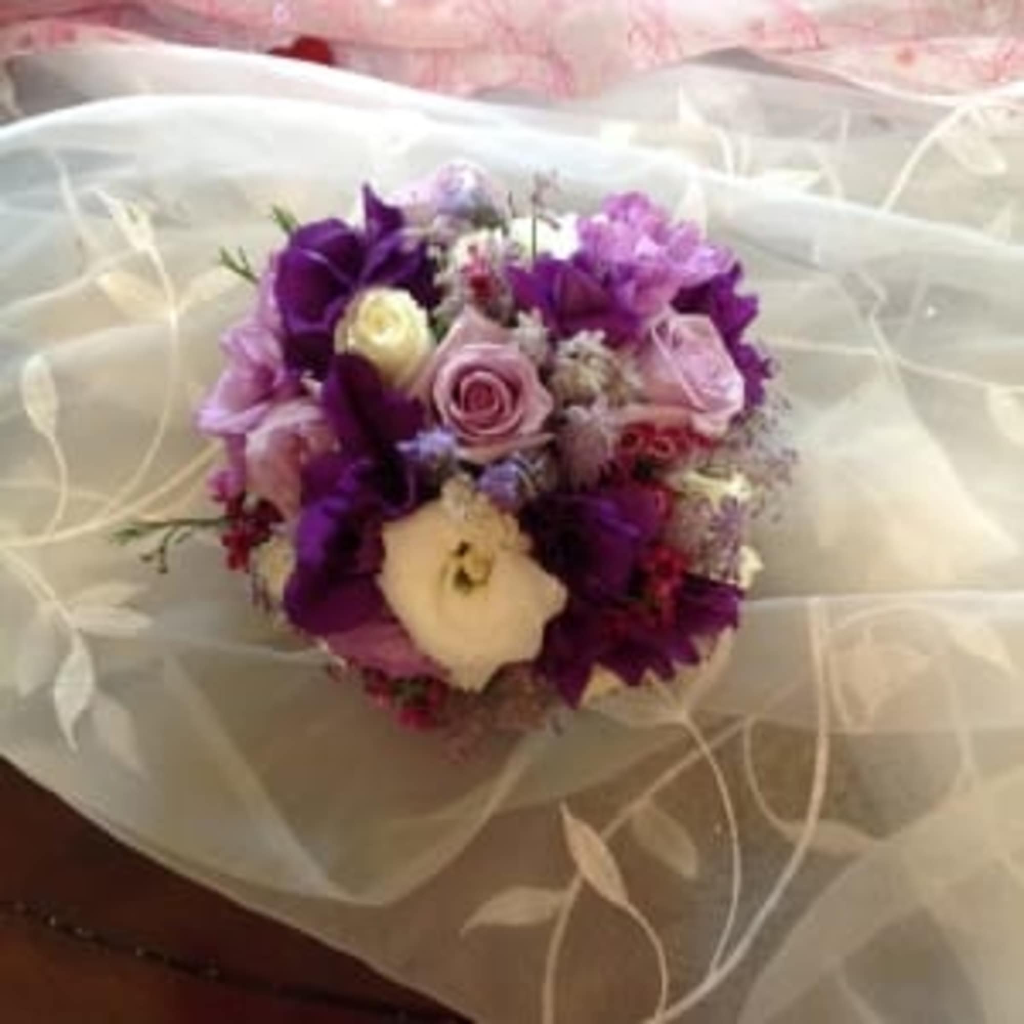 Bouquet of purple and pink flowers wrapped in sheer white fabric