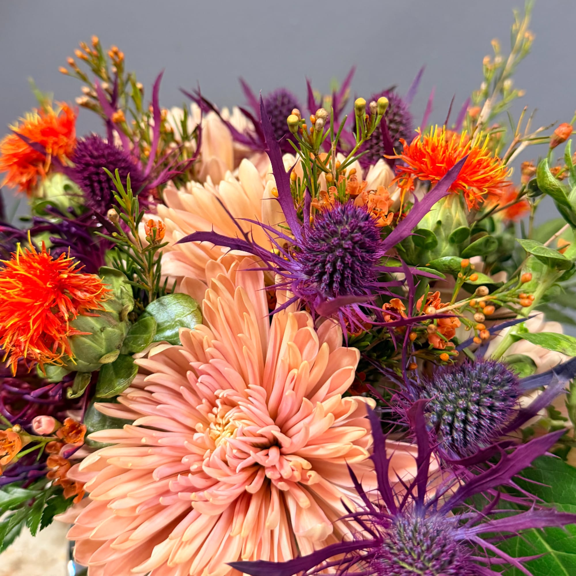 Bouquet of peach and purple flowers with orange accents