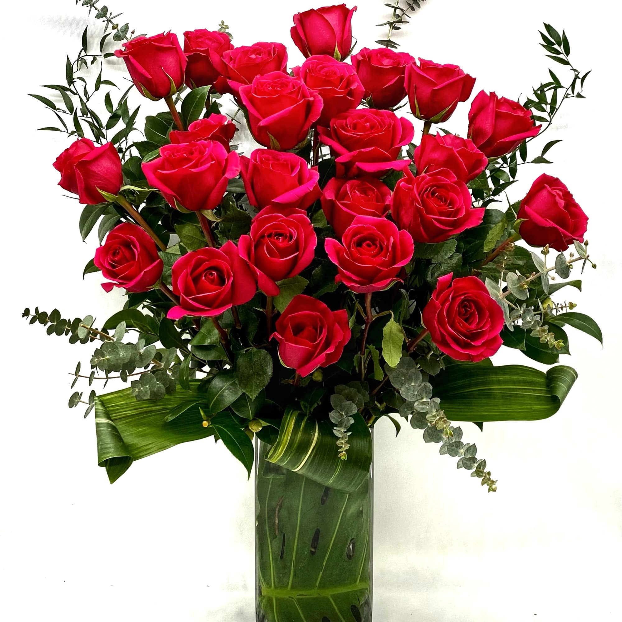 Bouquet of red roses in a glass vase with greenery