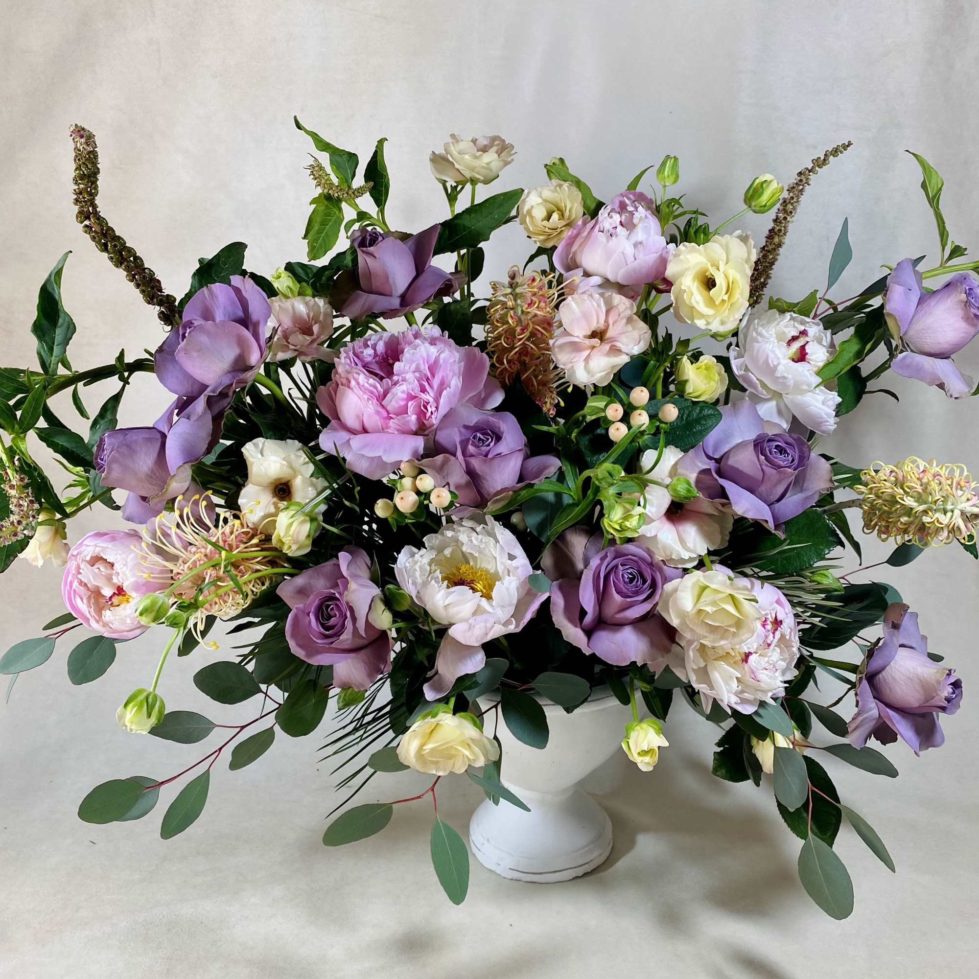 Lavender and white floral arrangement in a white pedestal vase