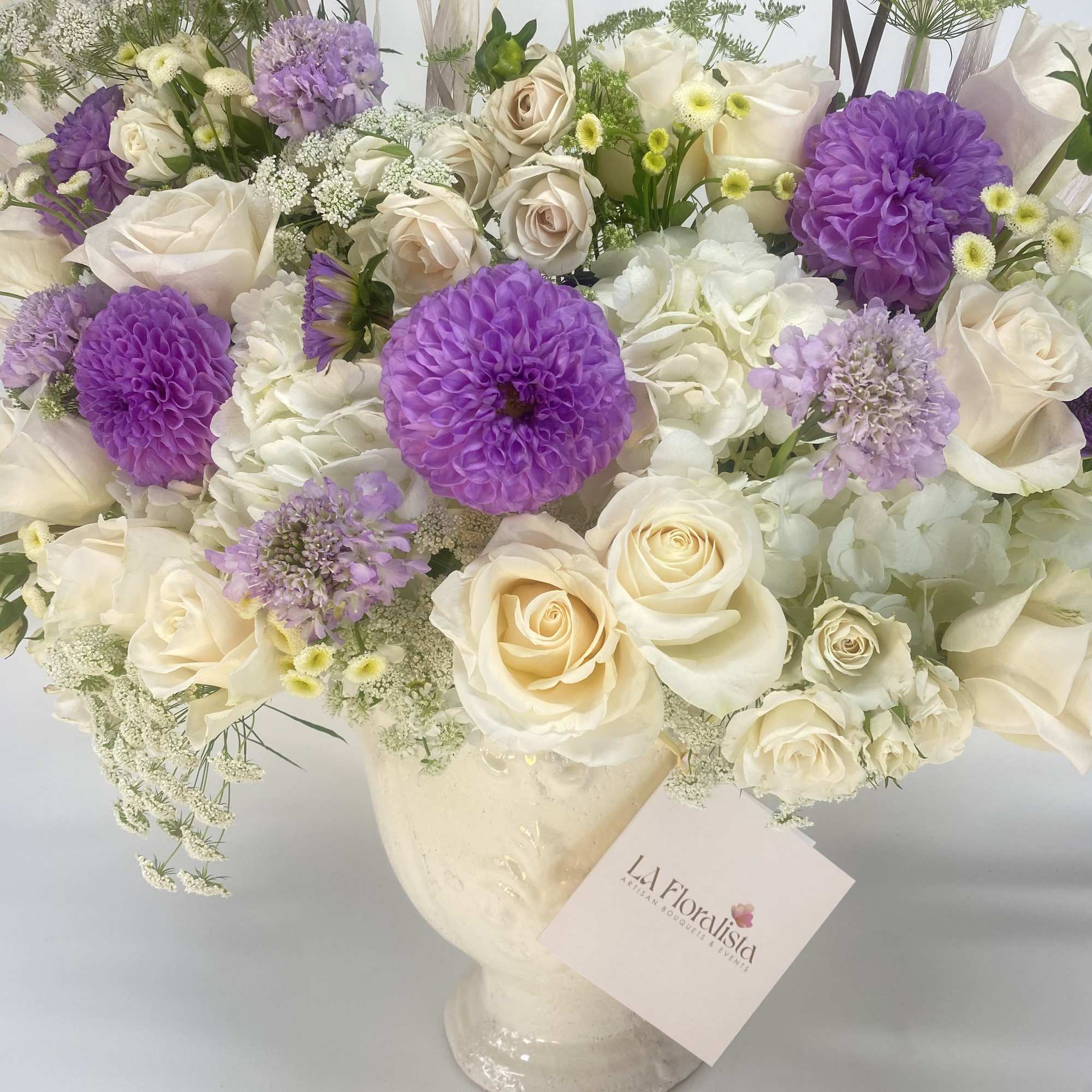 Cream and purple bouquet of roses and dahlias in a white vase