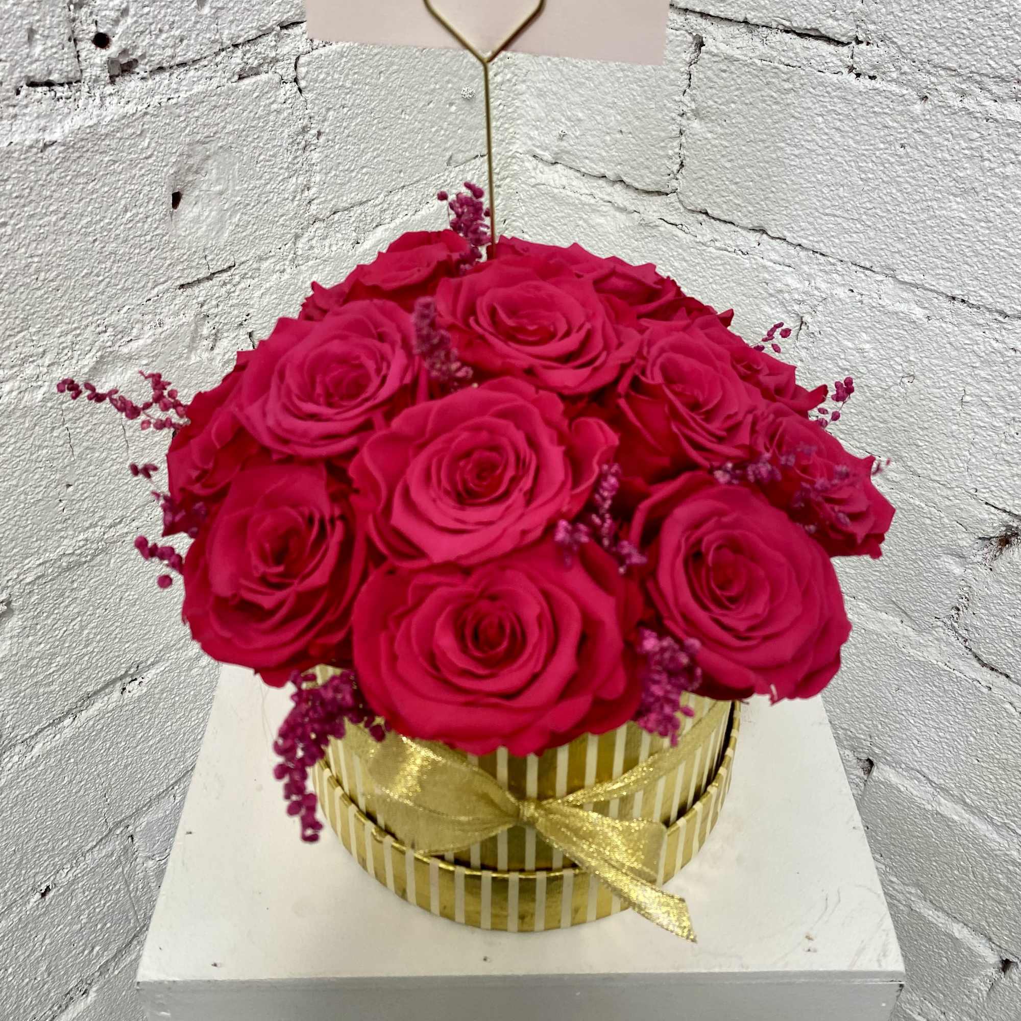 Hot pink roses in a gold striped box with a heart pick