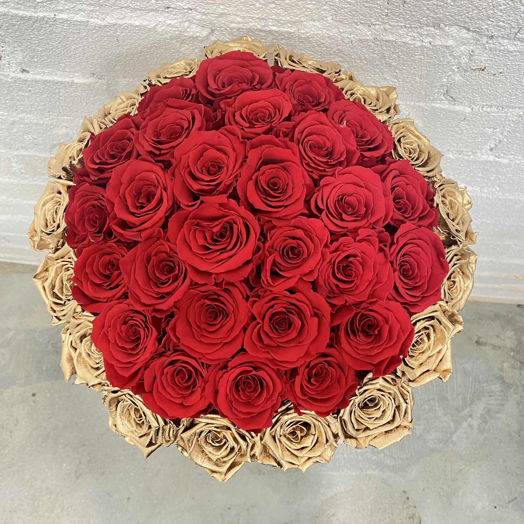 Round bouquet of red roses with gold roses around the edge