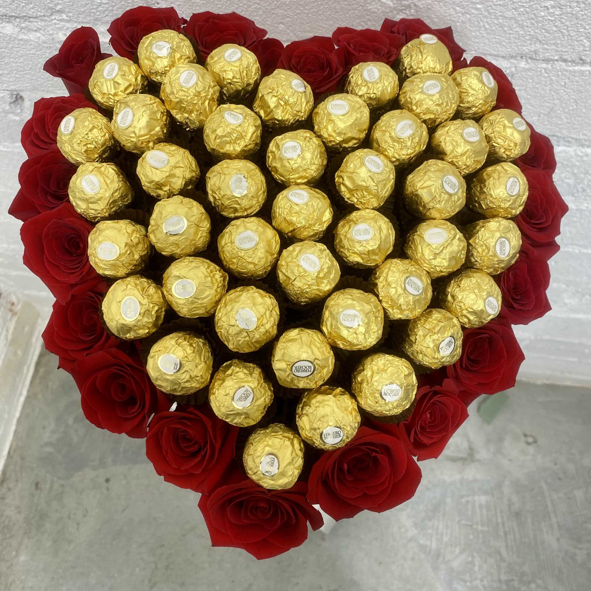 Heart-shaped bouquet of red roses with gold-wrapped chocolates