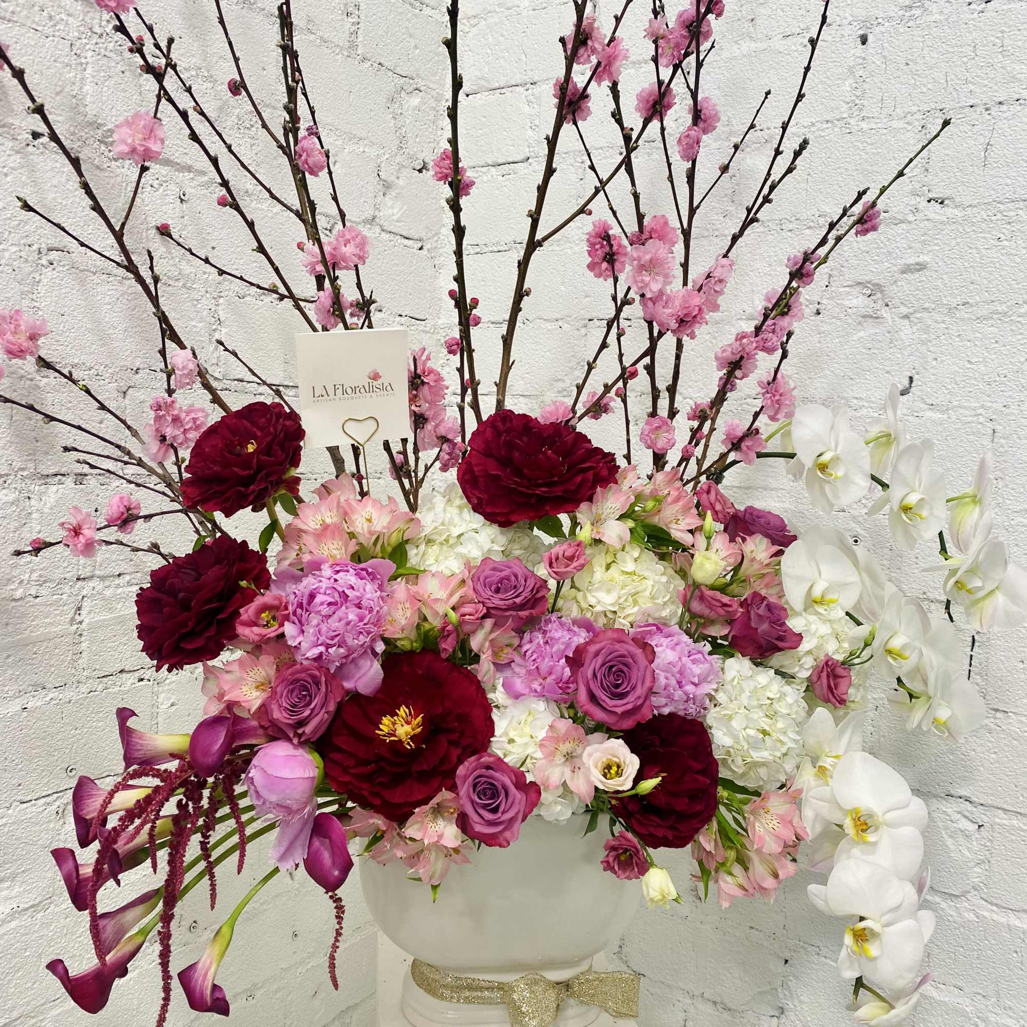 Large floral arrangement with pink, white, and burgundy blooms in a white vase