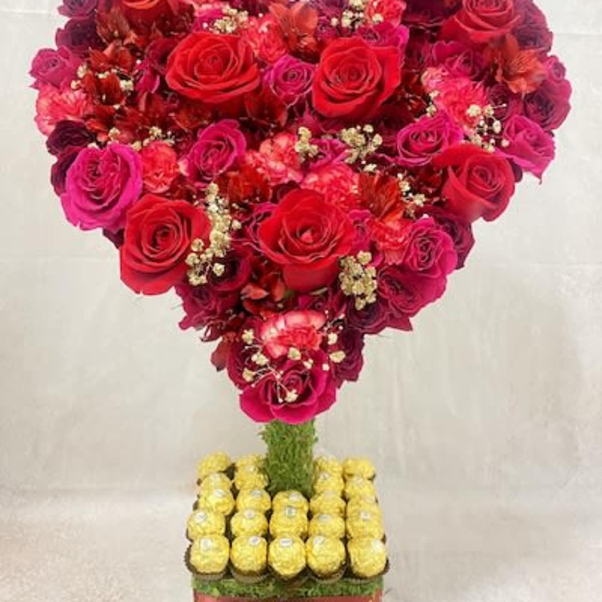 Heart-shaped rose arrangement on a square base with yellow chocolates