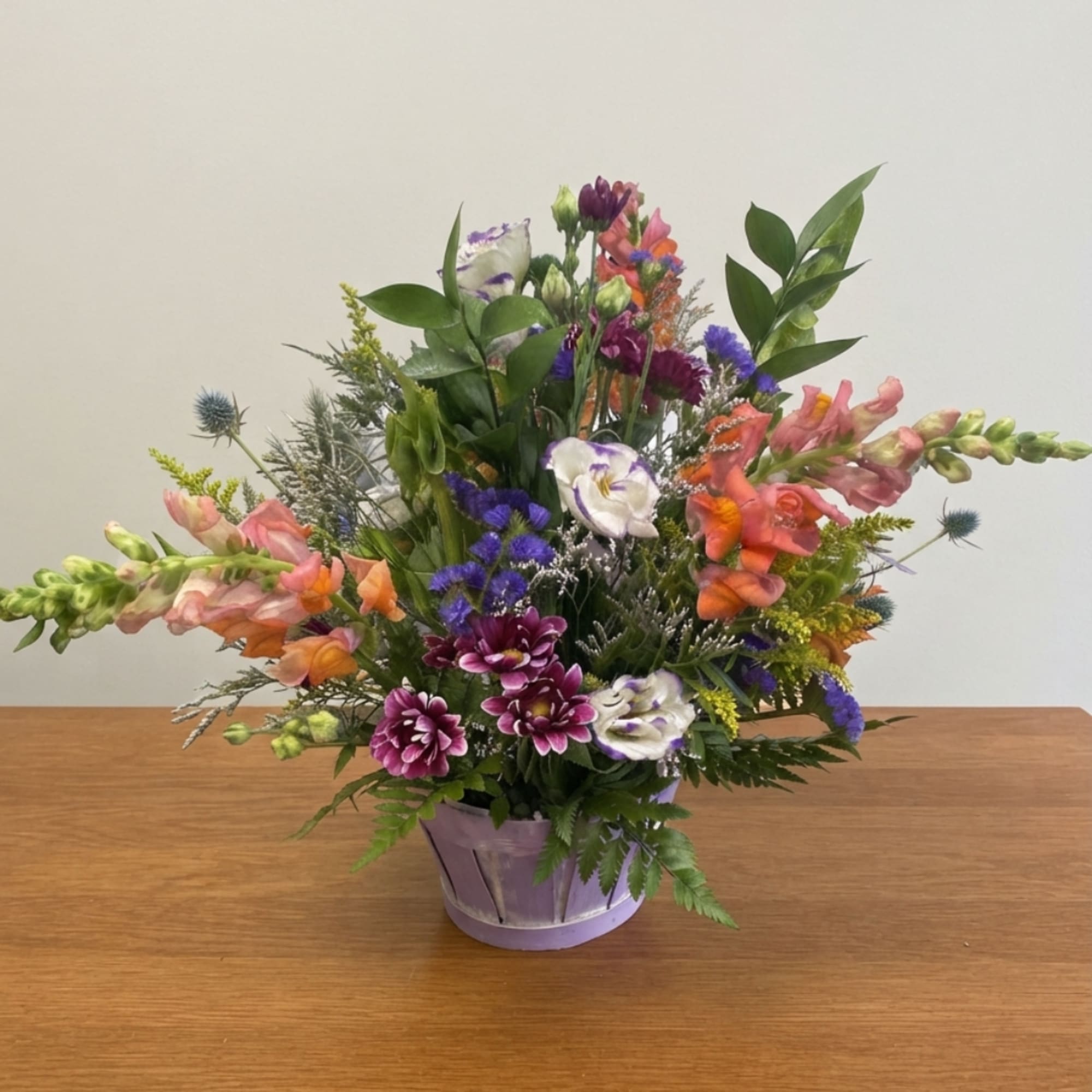 Mixed bouquet in a lavender basket with pink, purple, and white blooms