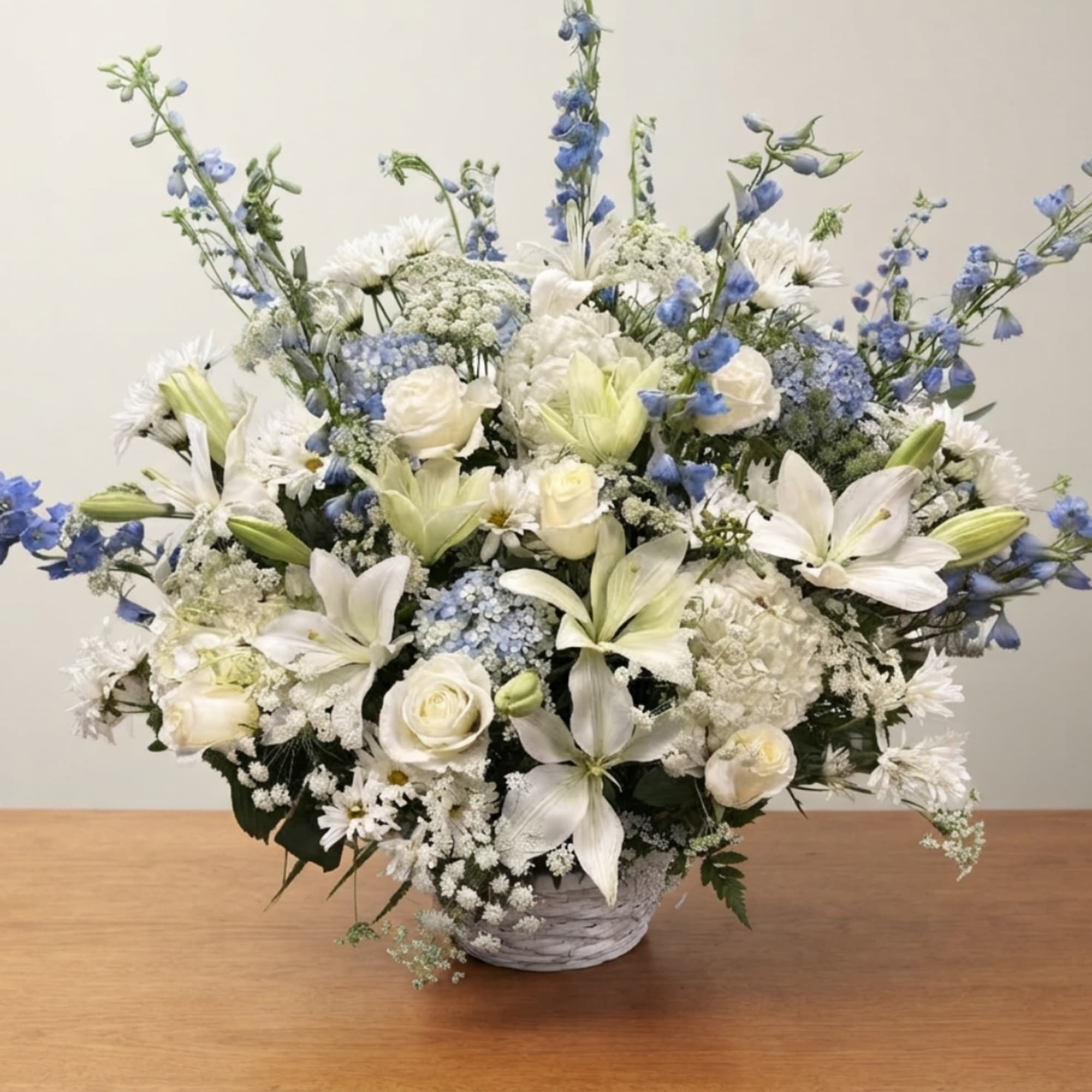 White and blue floral arrangement in a basket-style container