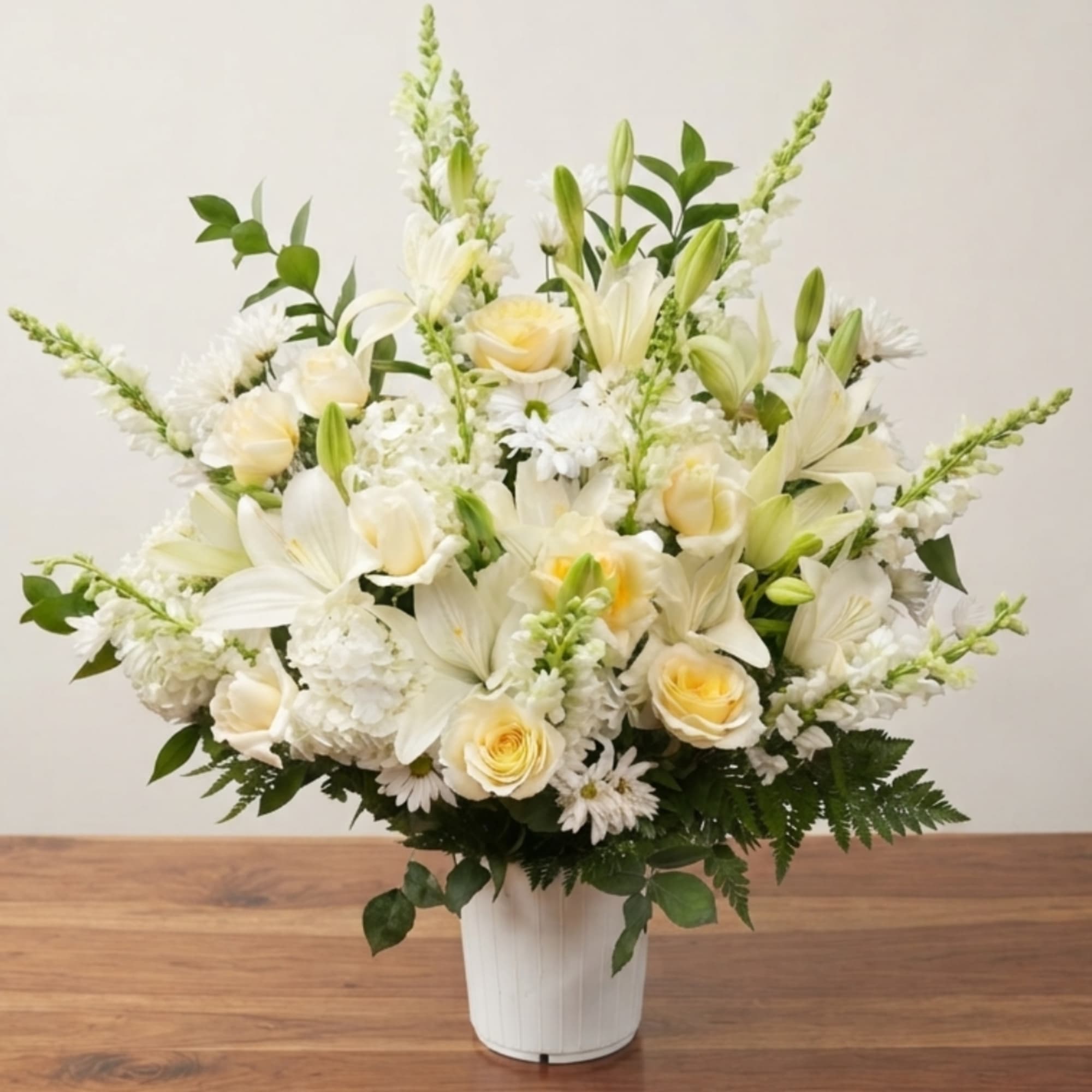 White floral arrangement with roses, lilies, and snapdragons in a white vase