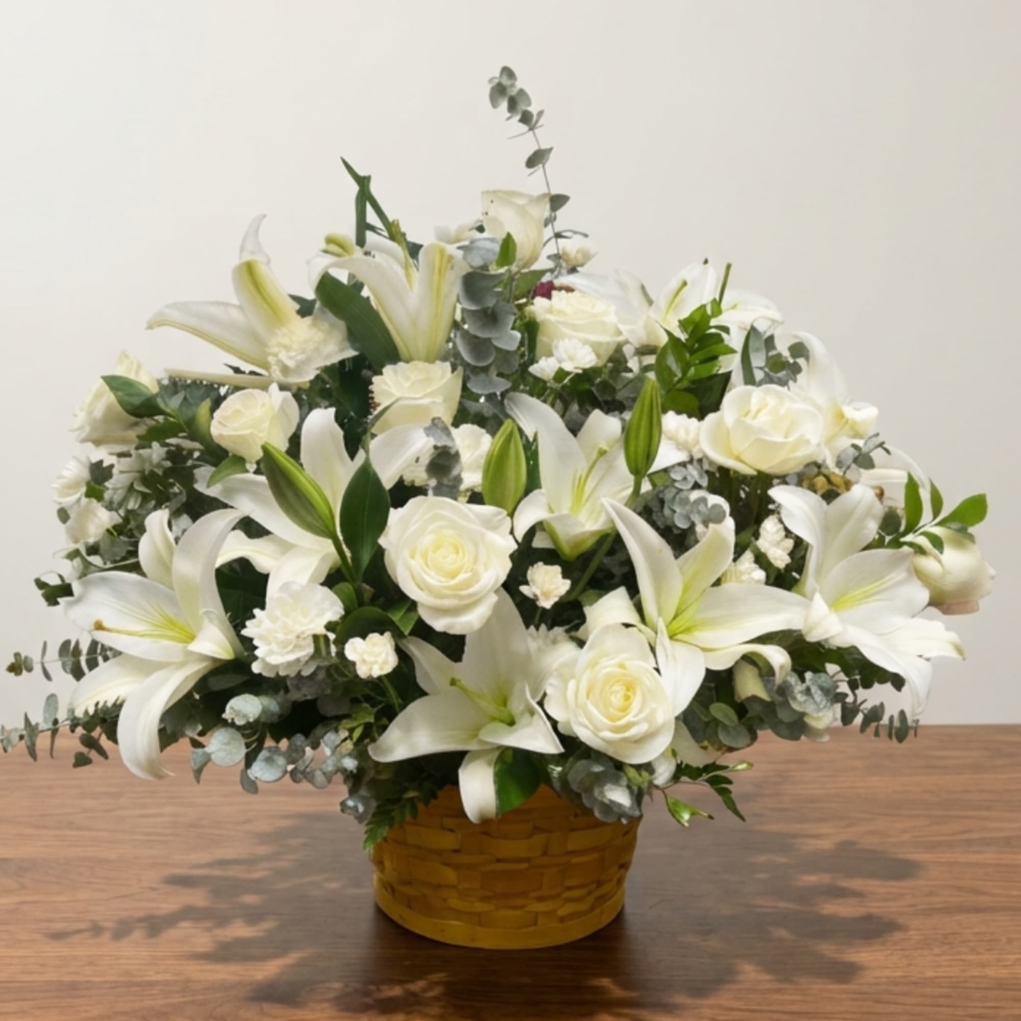 White lilies and roses arranged in a woven basket