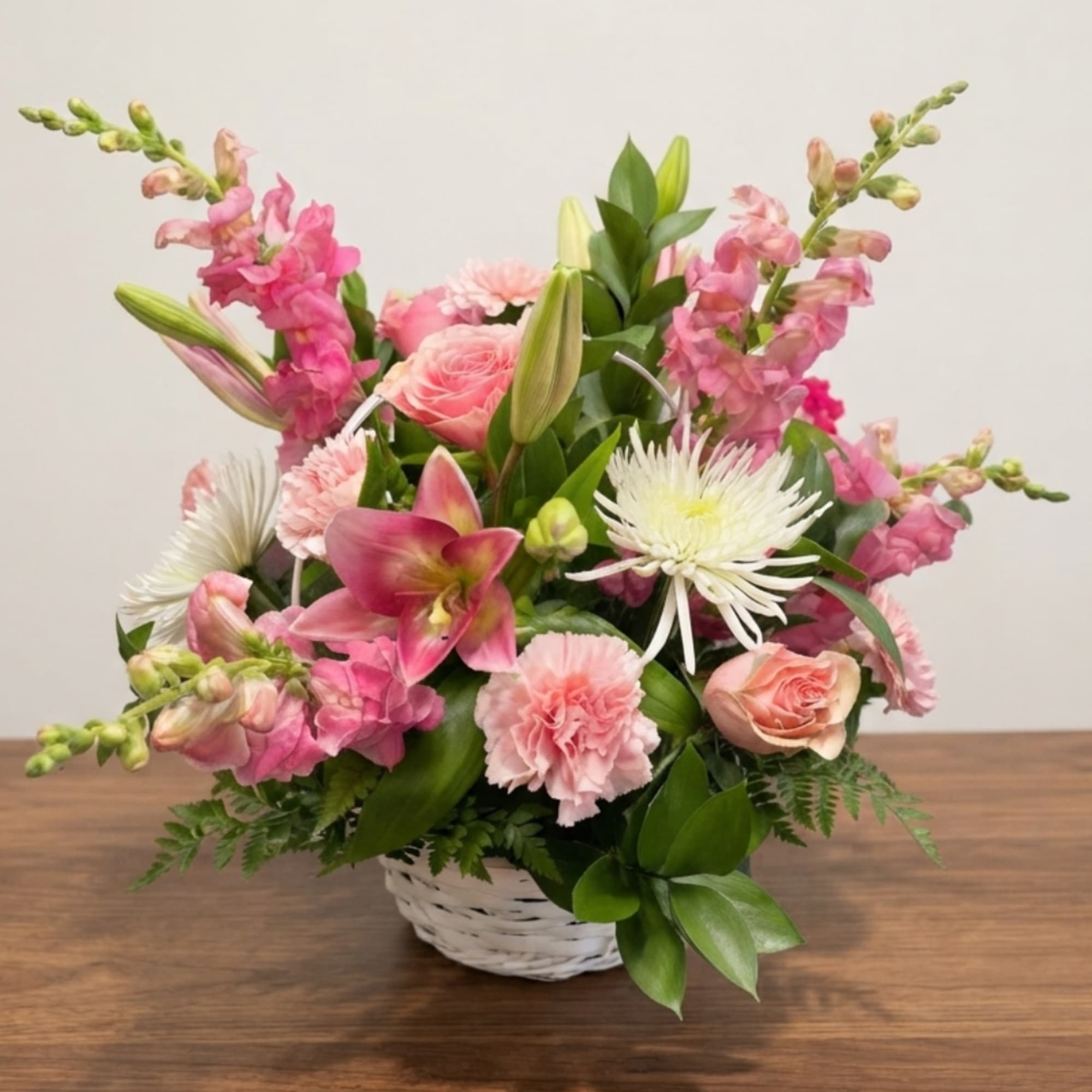 Pink and white mixed flower arrangement in a white basket