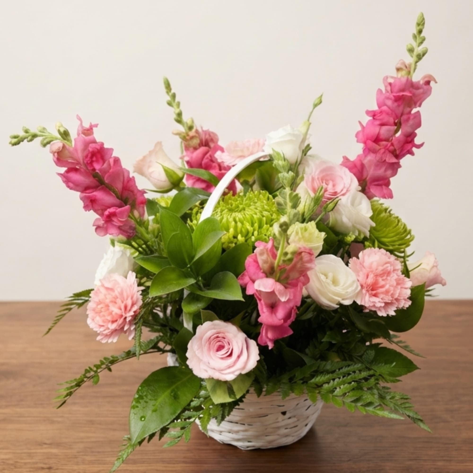 Pink and white flower arrangement in a white basket