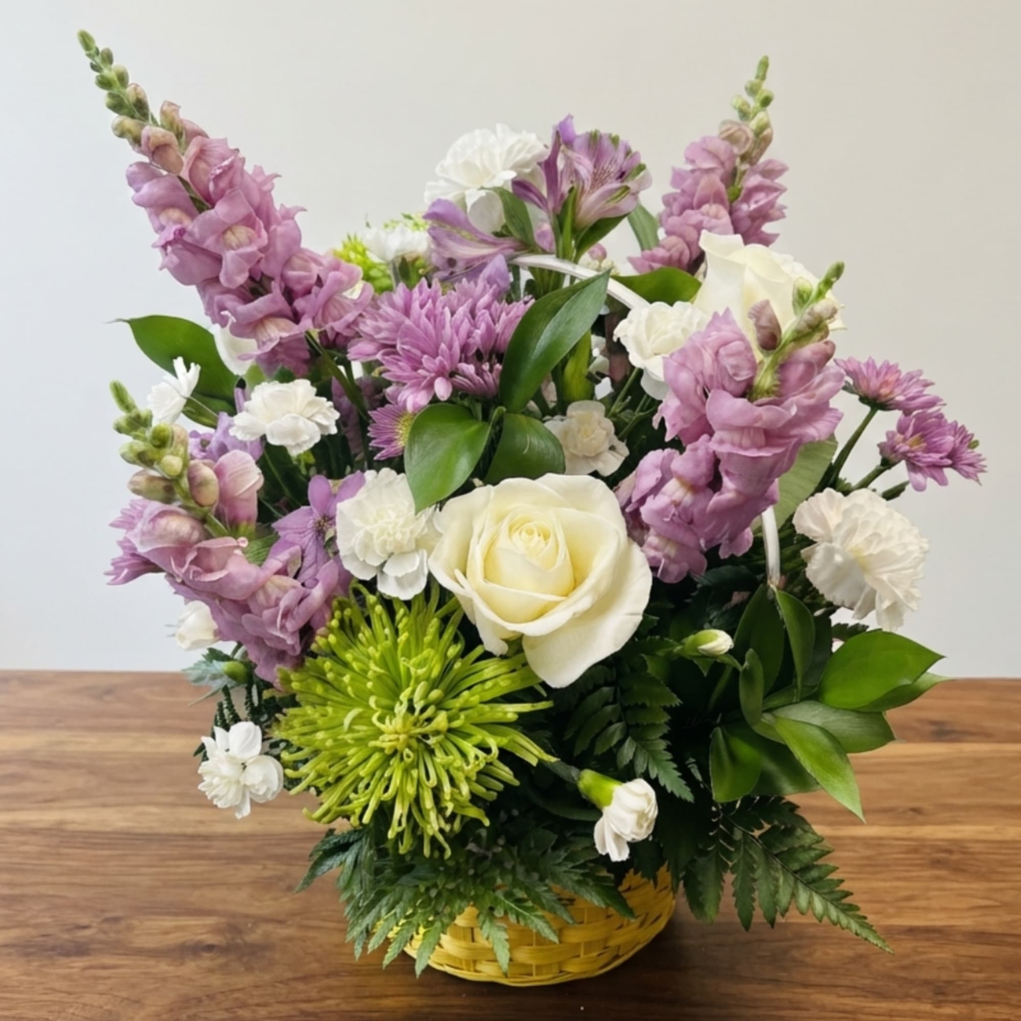 Basket arrangement with white roses, purple blooms, and green chrysanthemums
