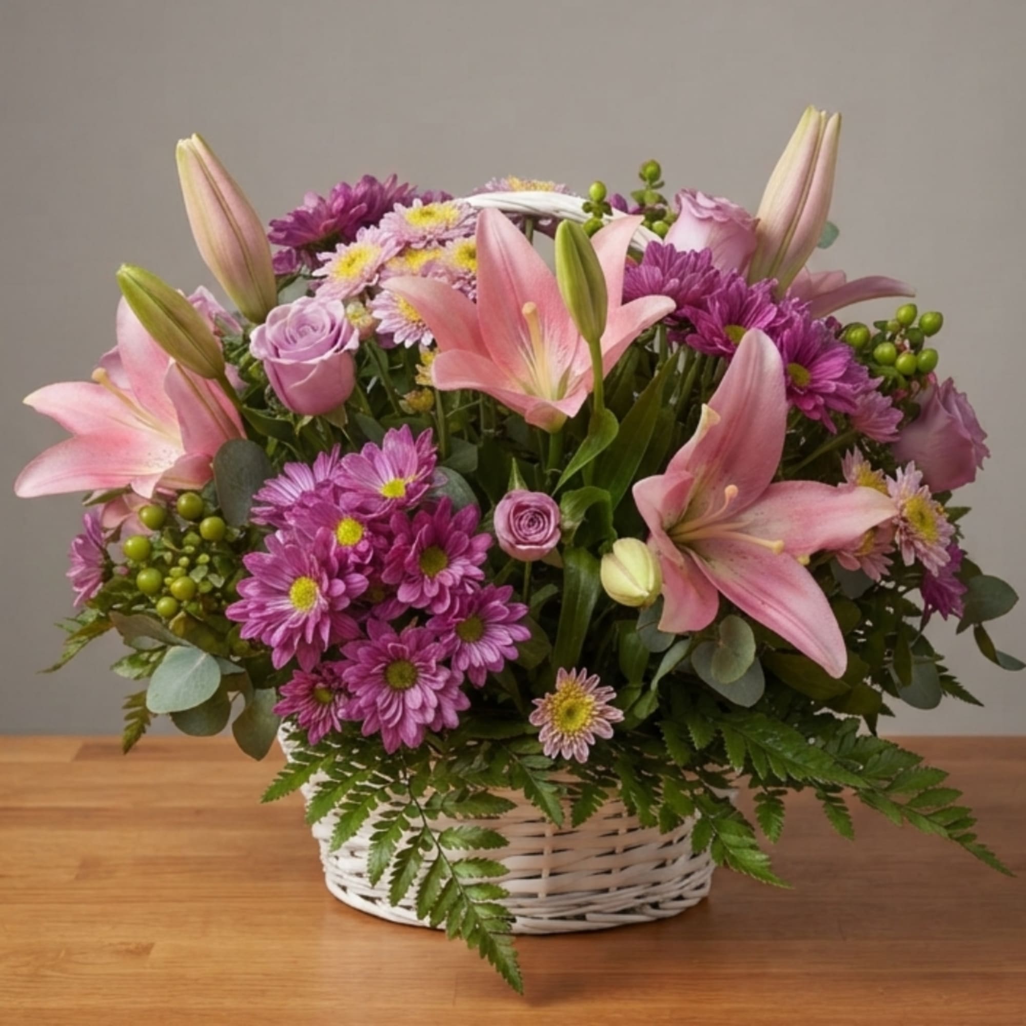 Pink lilies and purple flowers arranged in a white basket, photo 3 of 3