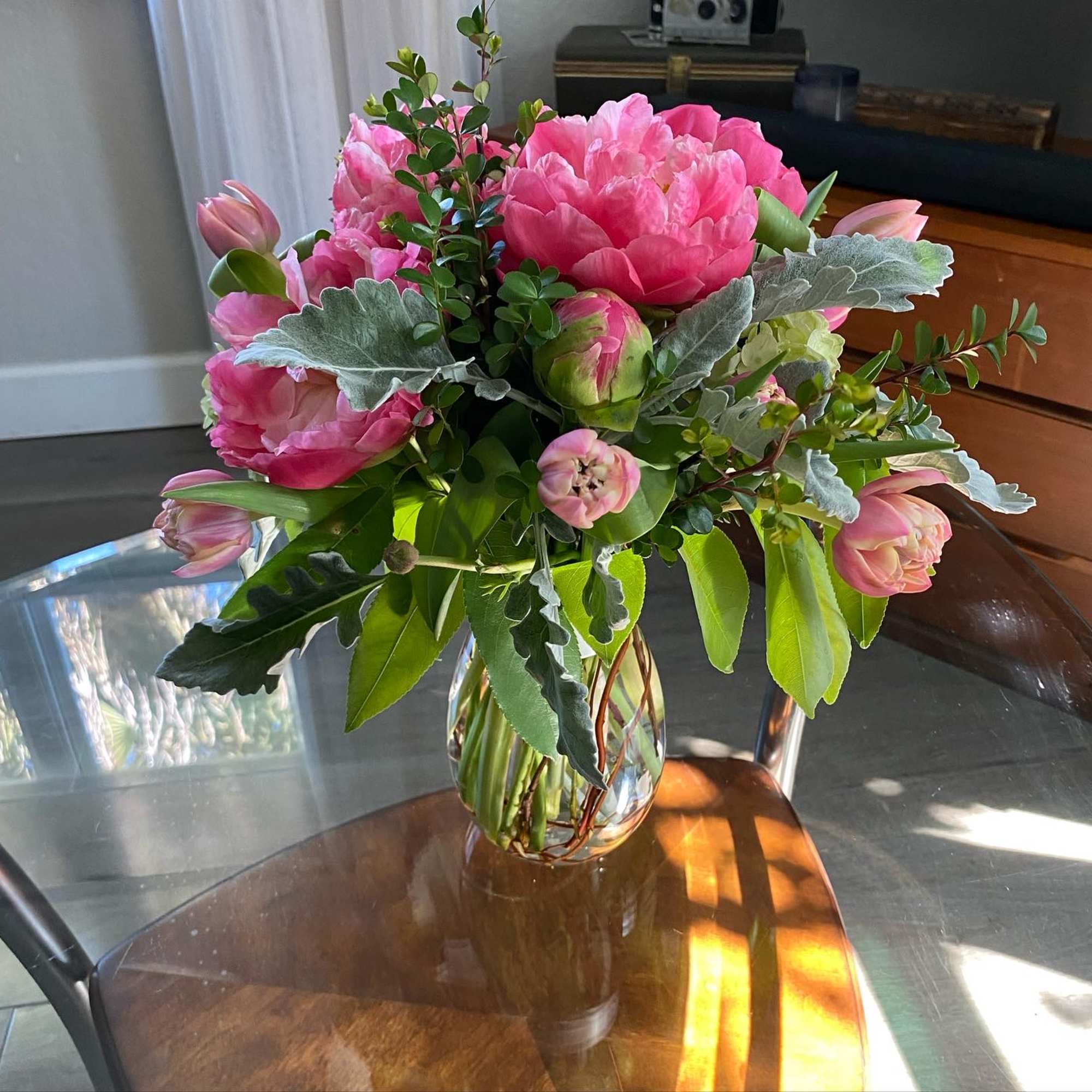 Pink tulips and peonies arranged in a clear glass vase