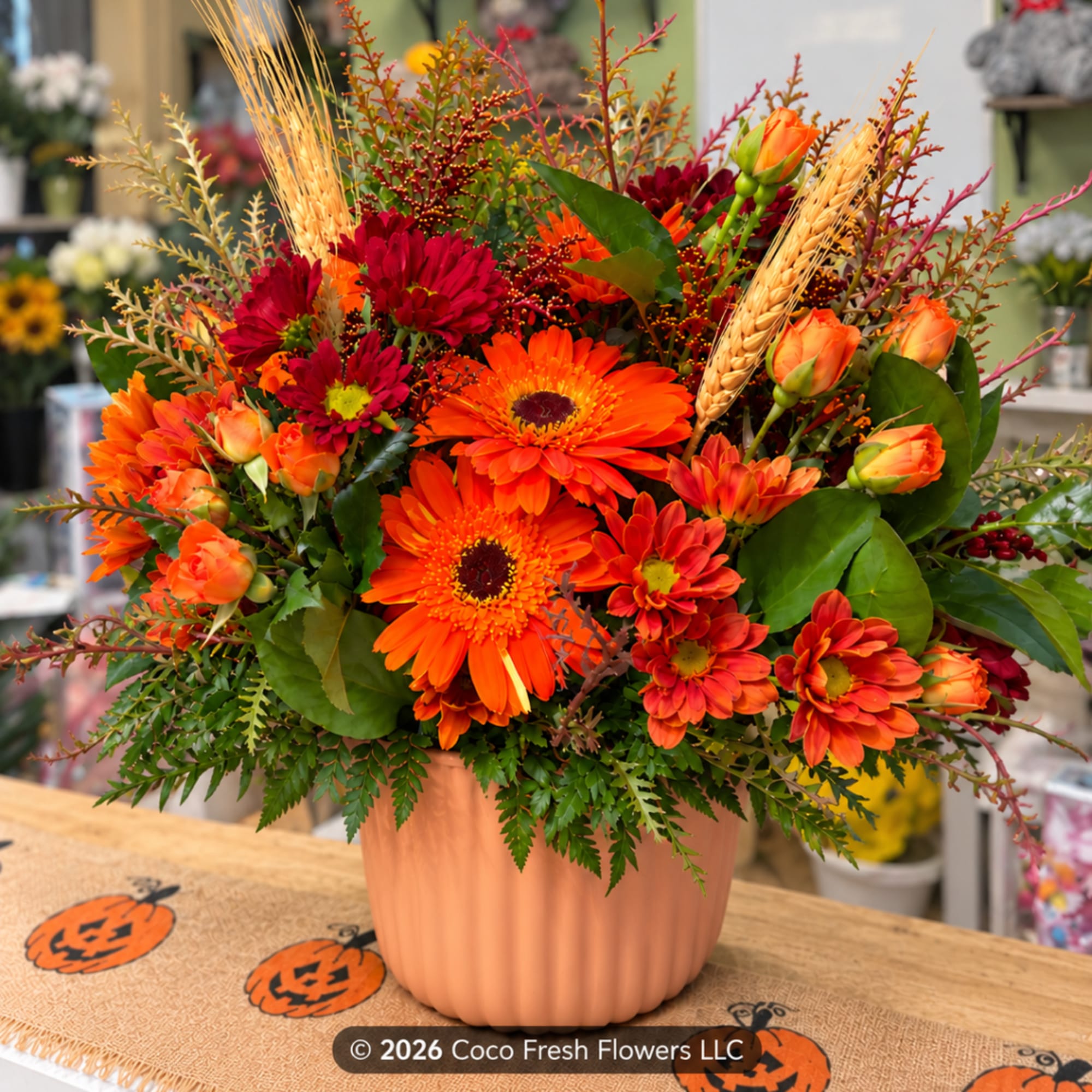Orange and red mixed flower arrangement in a peach vase, photo 3 of 3