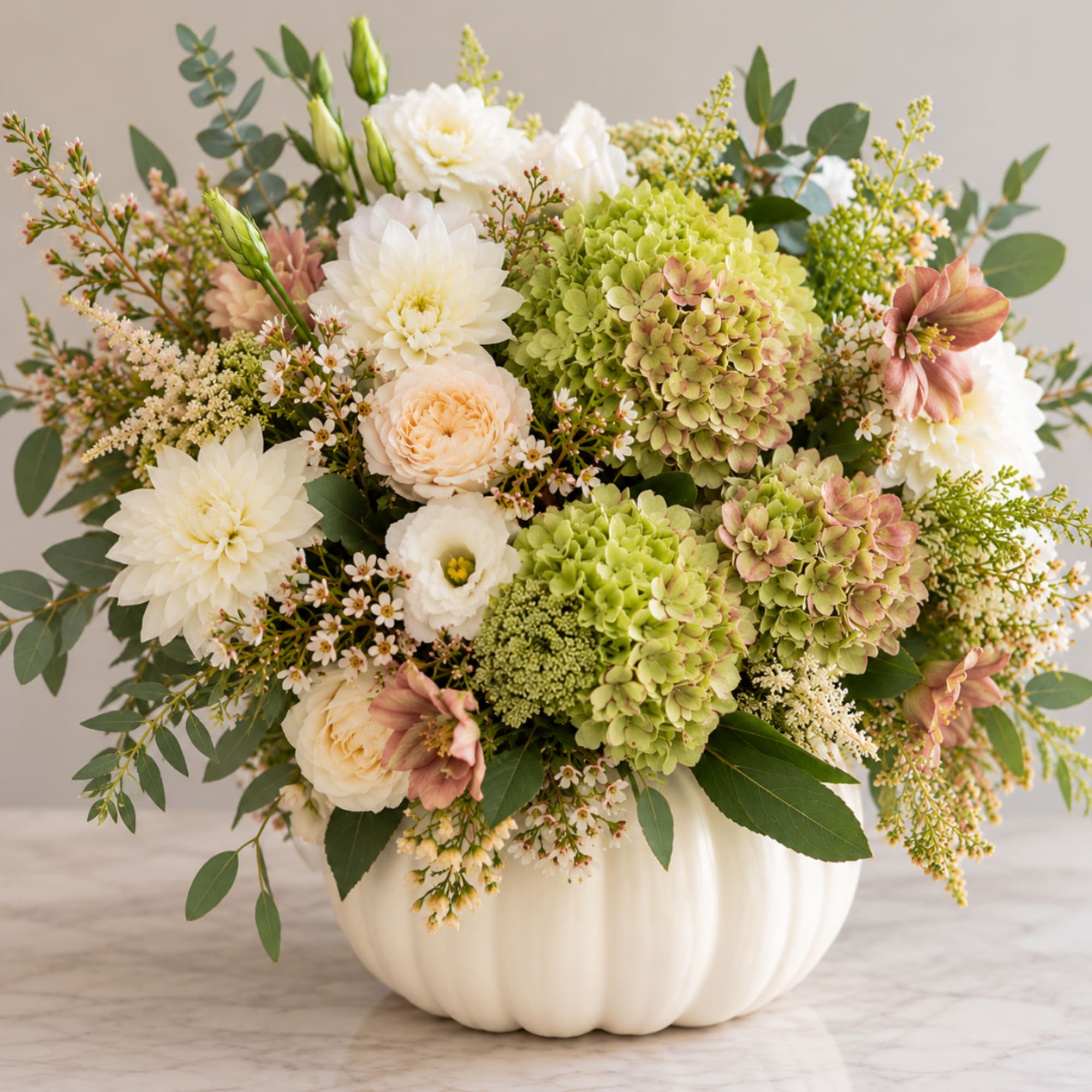 Mixed white and green floral arrangement in a white pumpkin vase