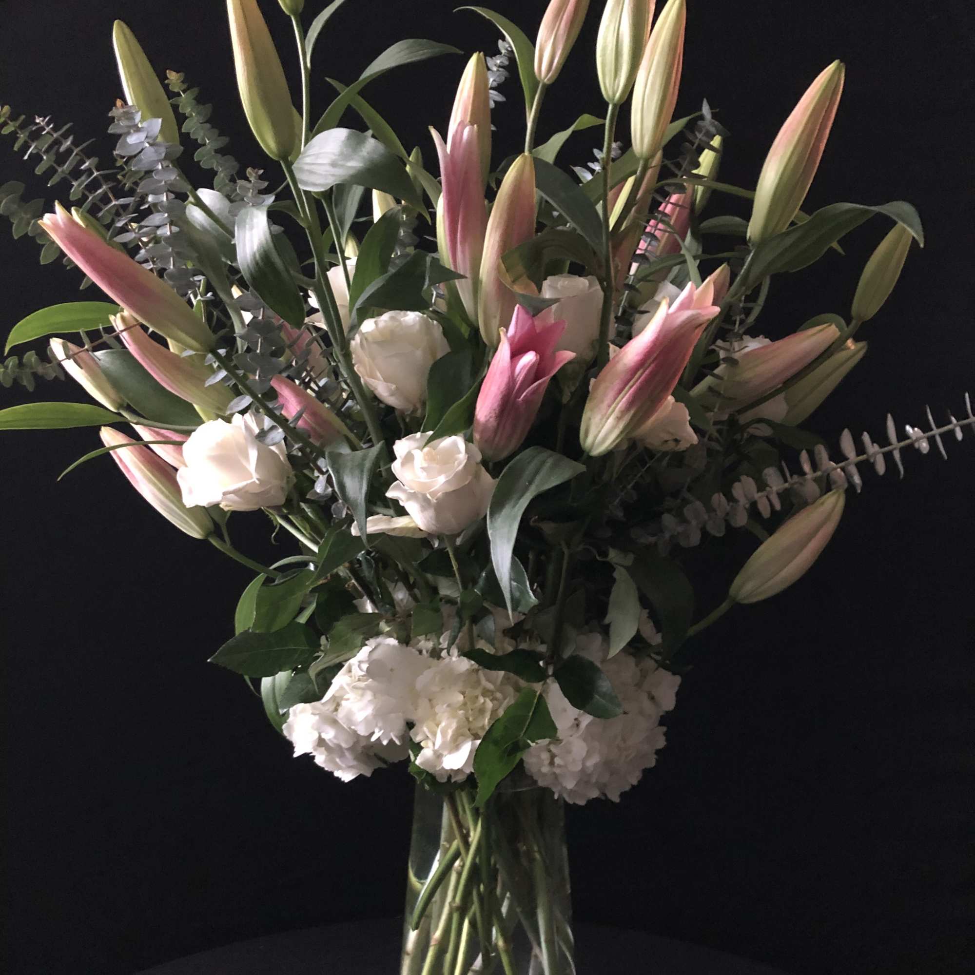 Bouquet of pink lilies and white roses in a clear glass vase