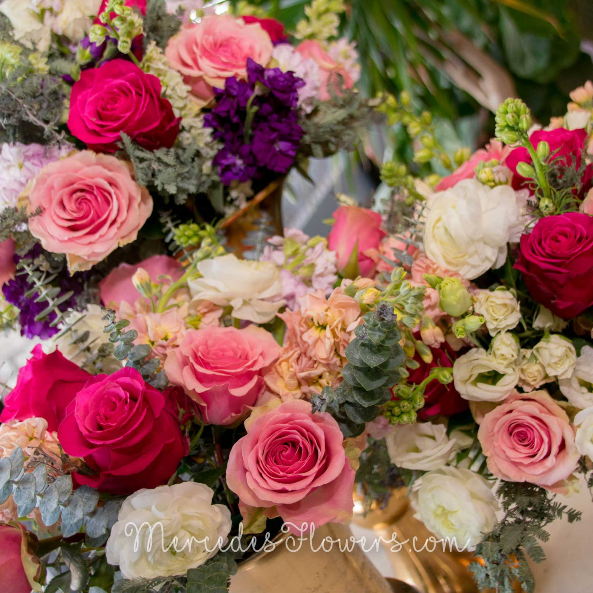 Bouquets of pink, white, and purple roses arranged in gold vases
