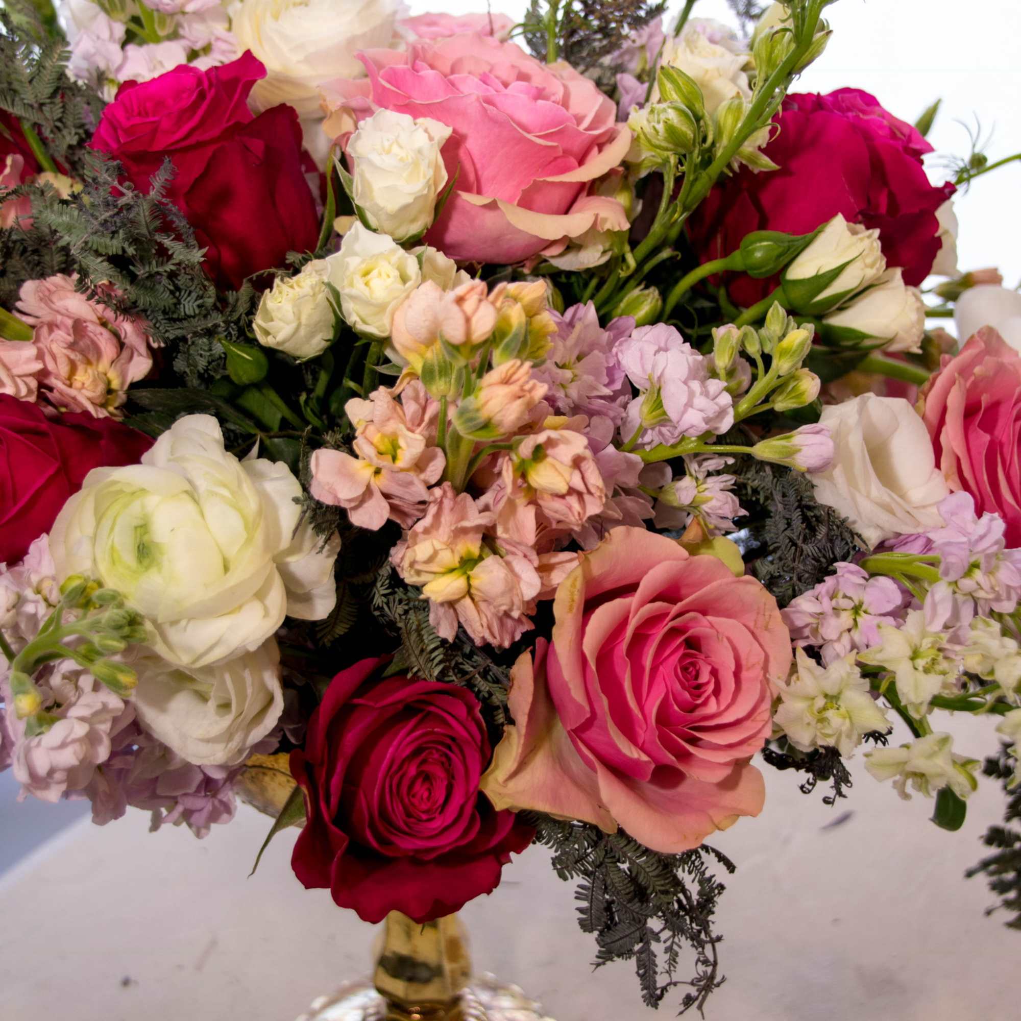 Mixed bouquet of pink, red, and white roses in a gold vase