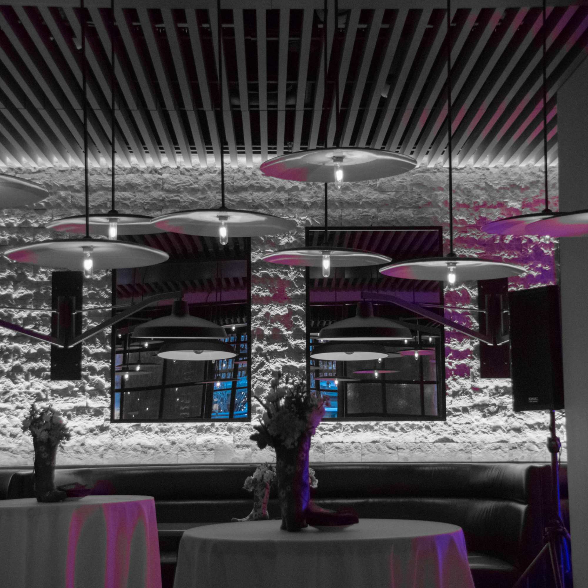 Floral centerpieces on round tables in a dimly lit lounge