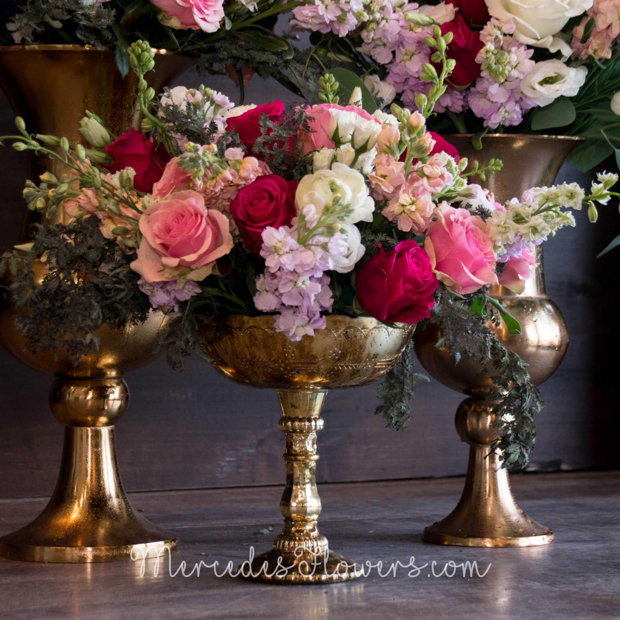 Pink and white rose arrangement in a gold pedestal vase