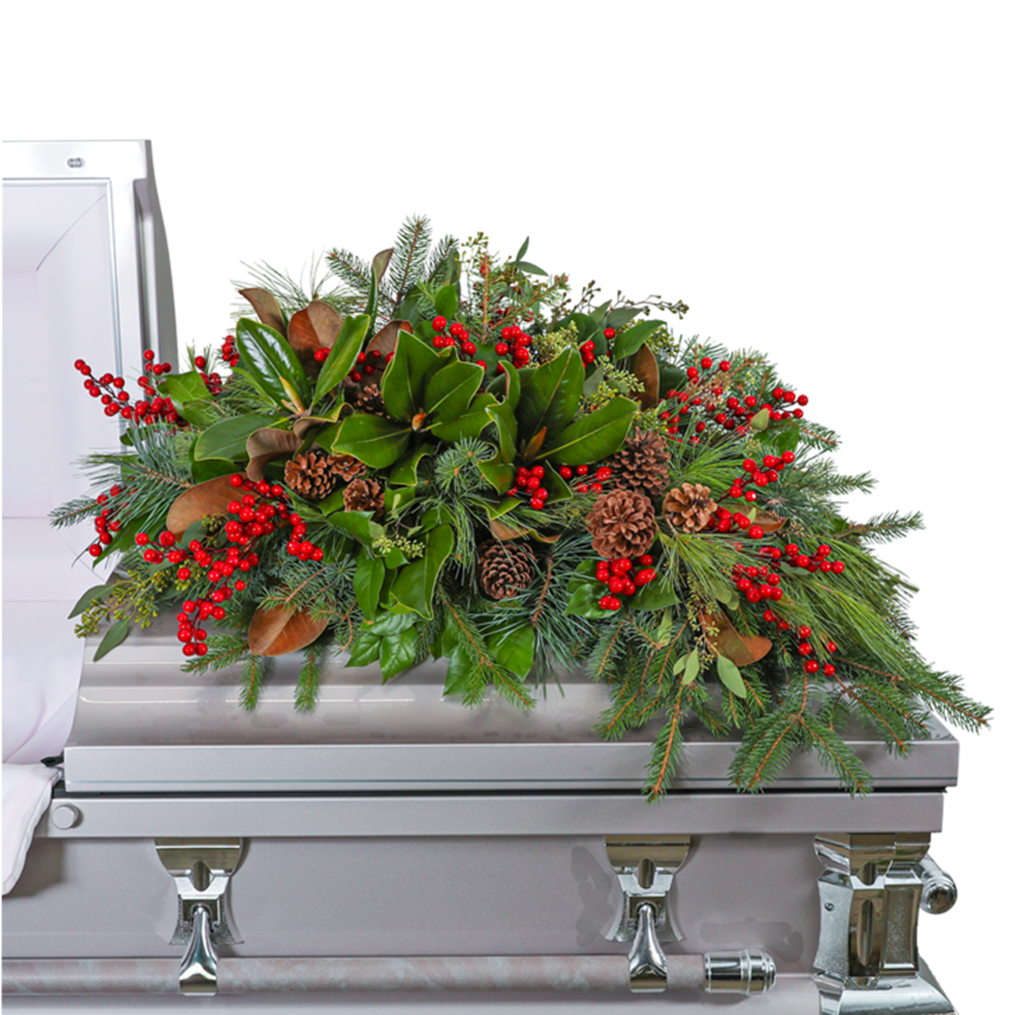 Holiday greenery and red berry casket spray on a silver casket
