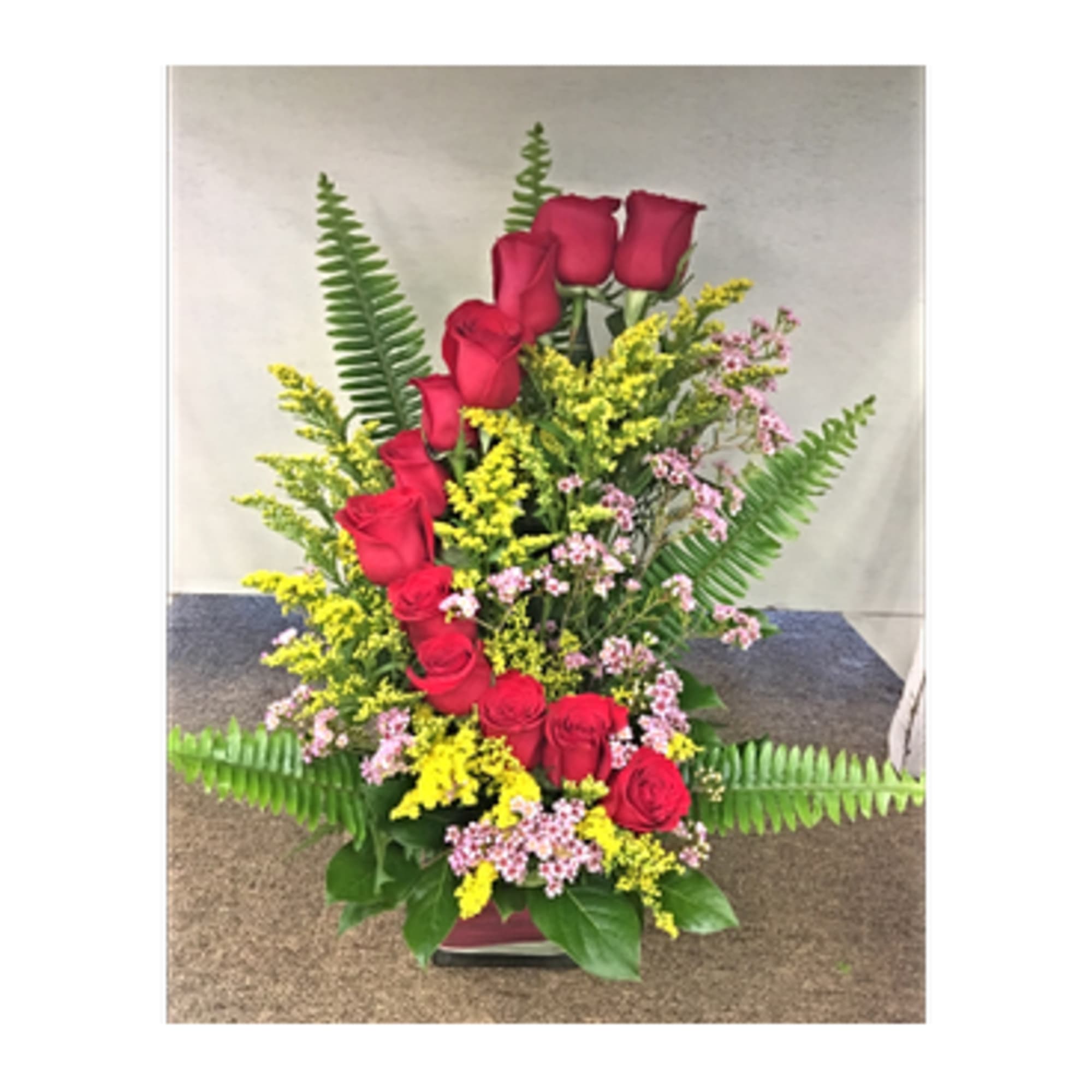Tall arrangement of red roses with yellow and pink filler flowers