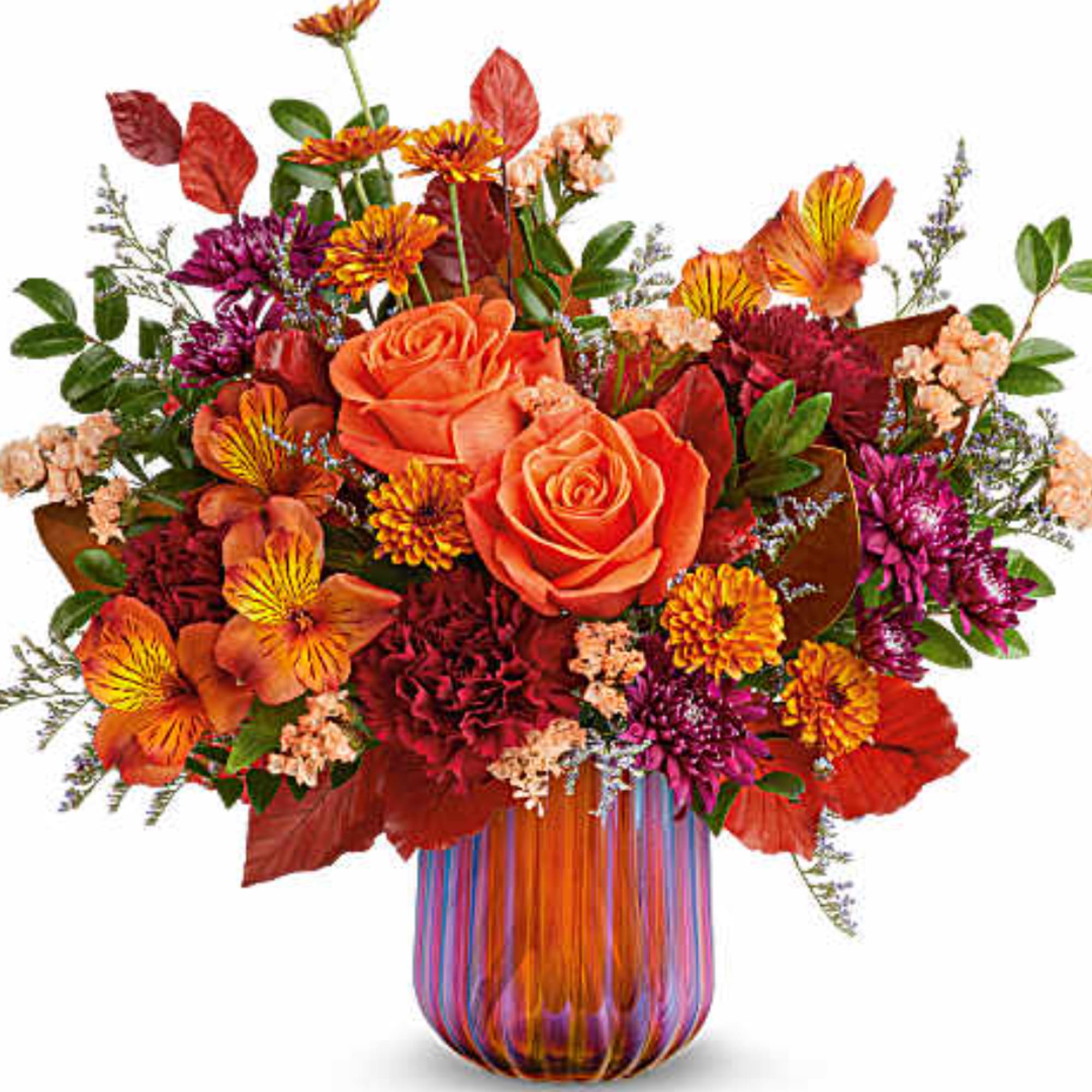 Orange roses and mixed autumn flowers in a striped glass vase