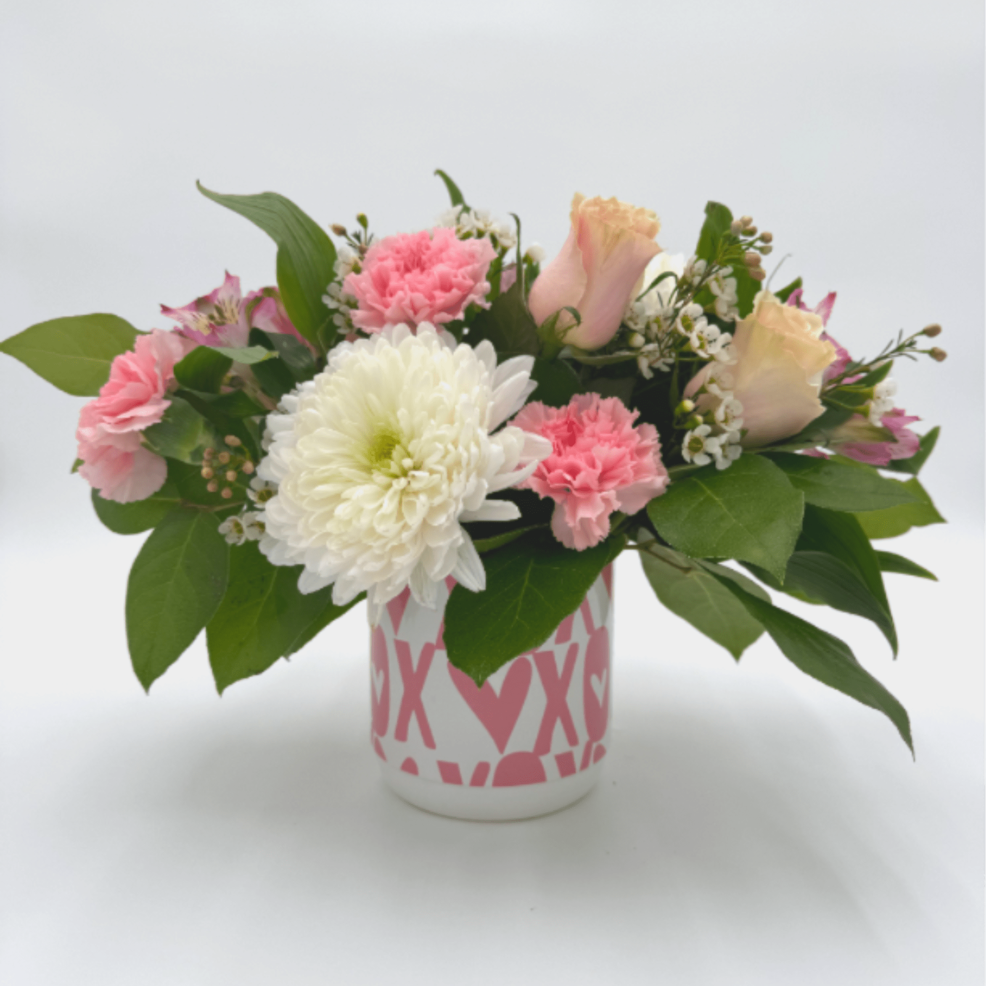 A delicate mix of blush roses, soft pink carnations, creamy white mums