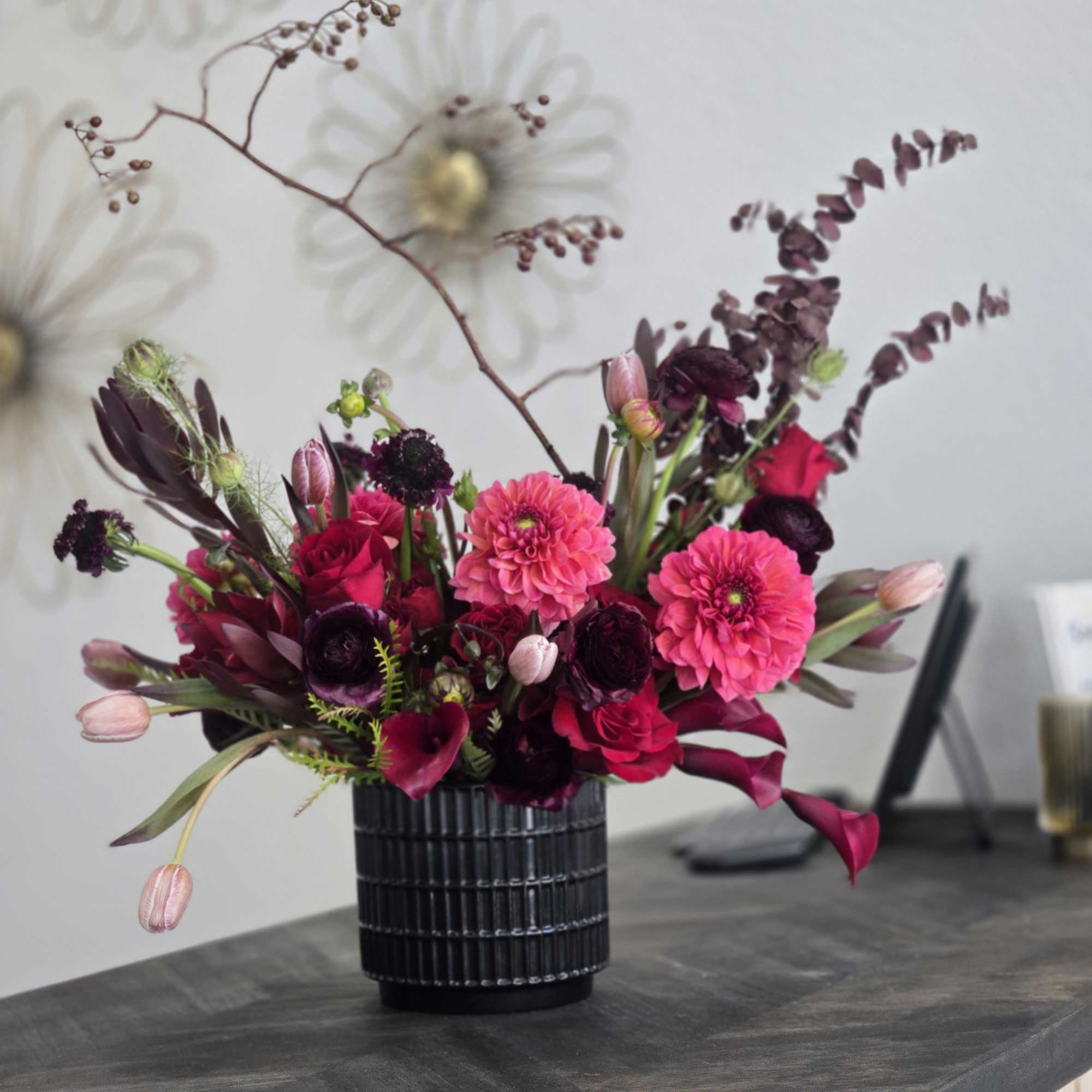 Pink and burgundy floral arrangement in a black vase