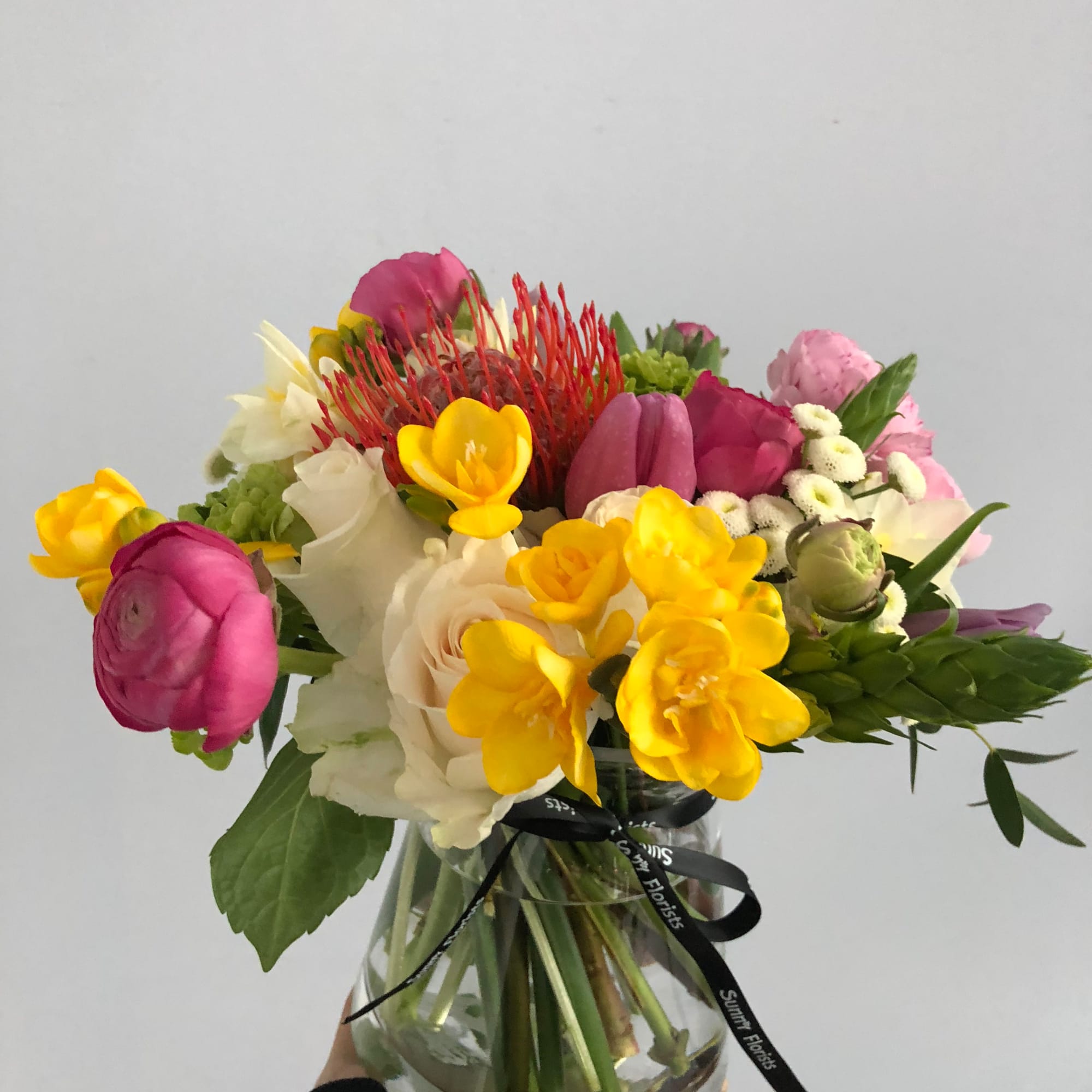 Mixed bouquet of bright flowers in a clear glass vase