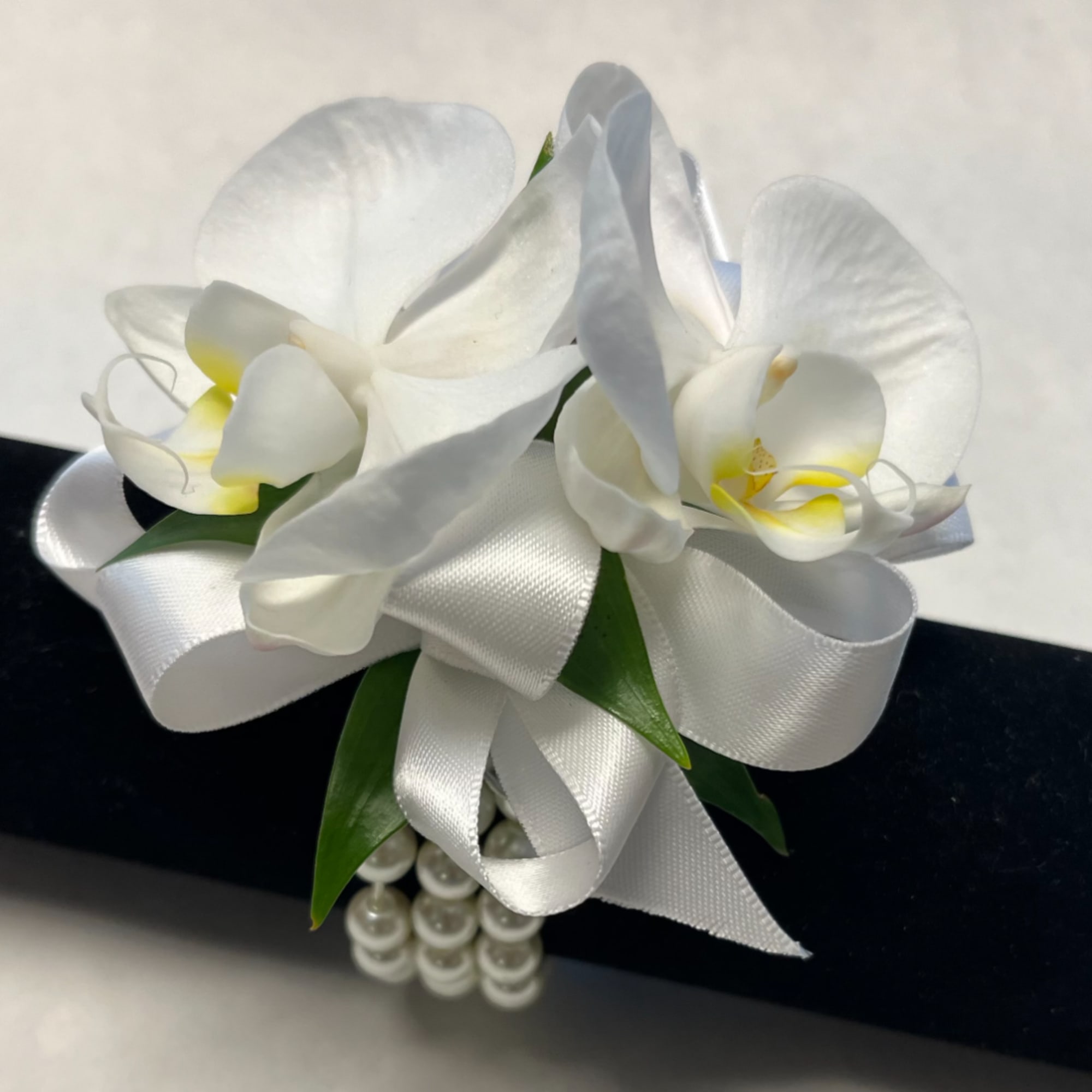 White orchid corsage with satin ribbon and pearl accents