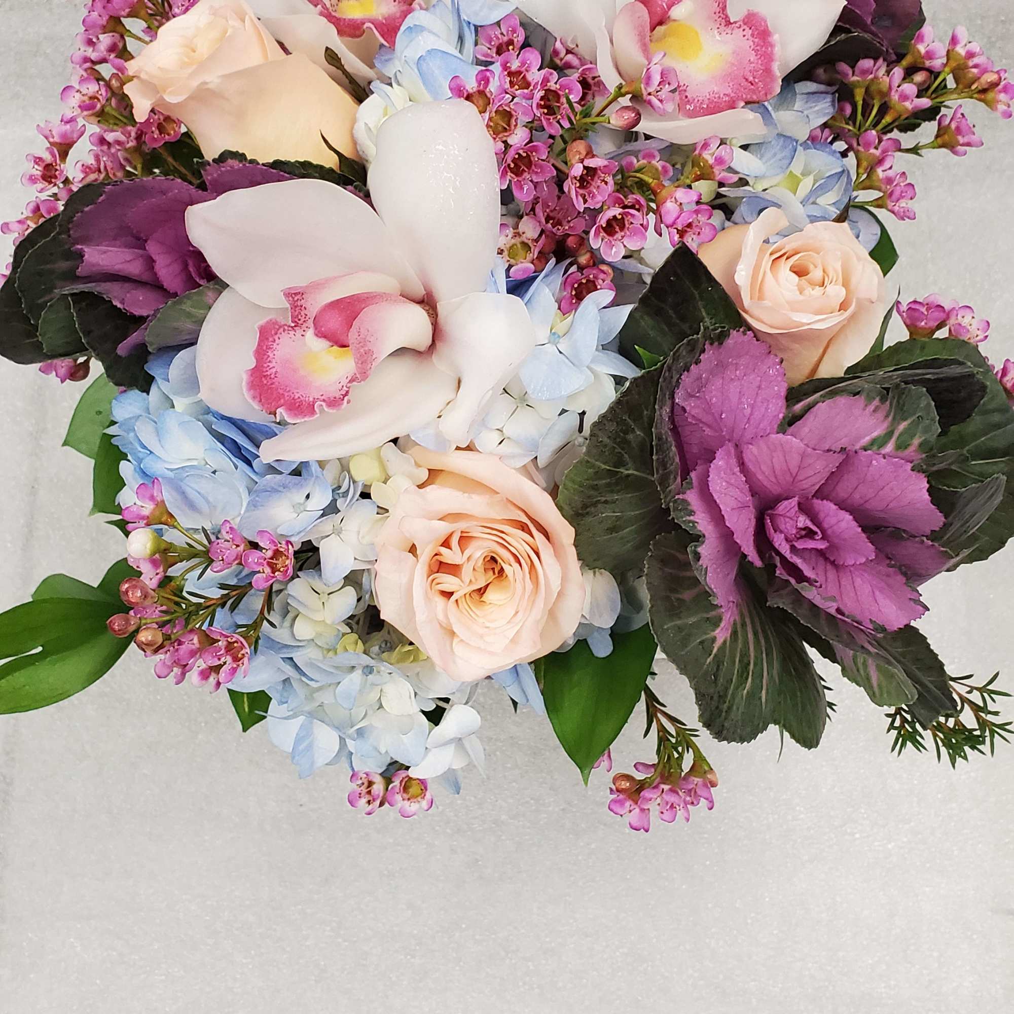 Bouquet with white orchids, pale roses, and blue hydrangeas