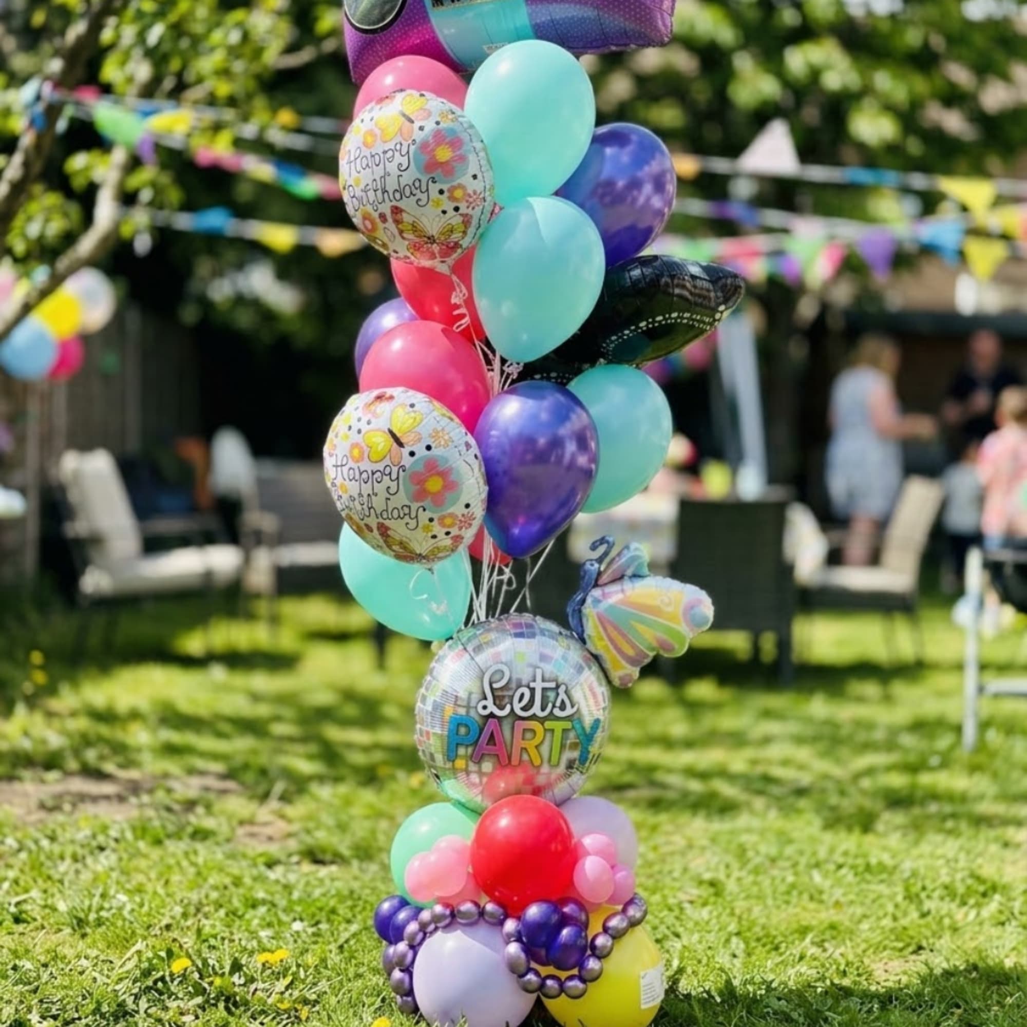 Cluster of colorful birthday balloons outdoors on grass