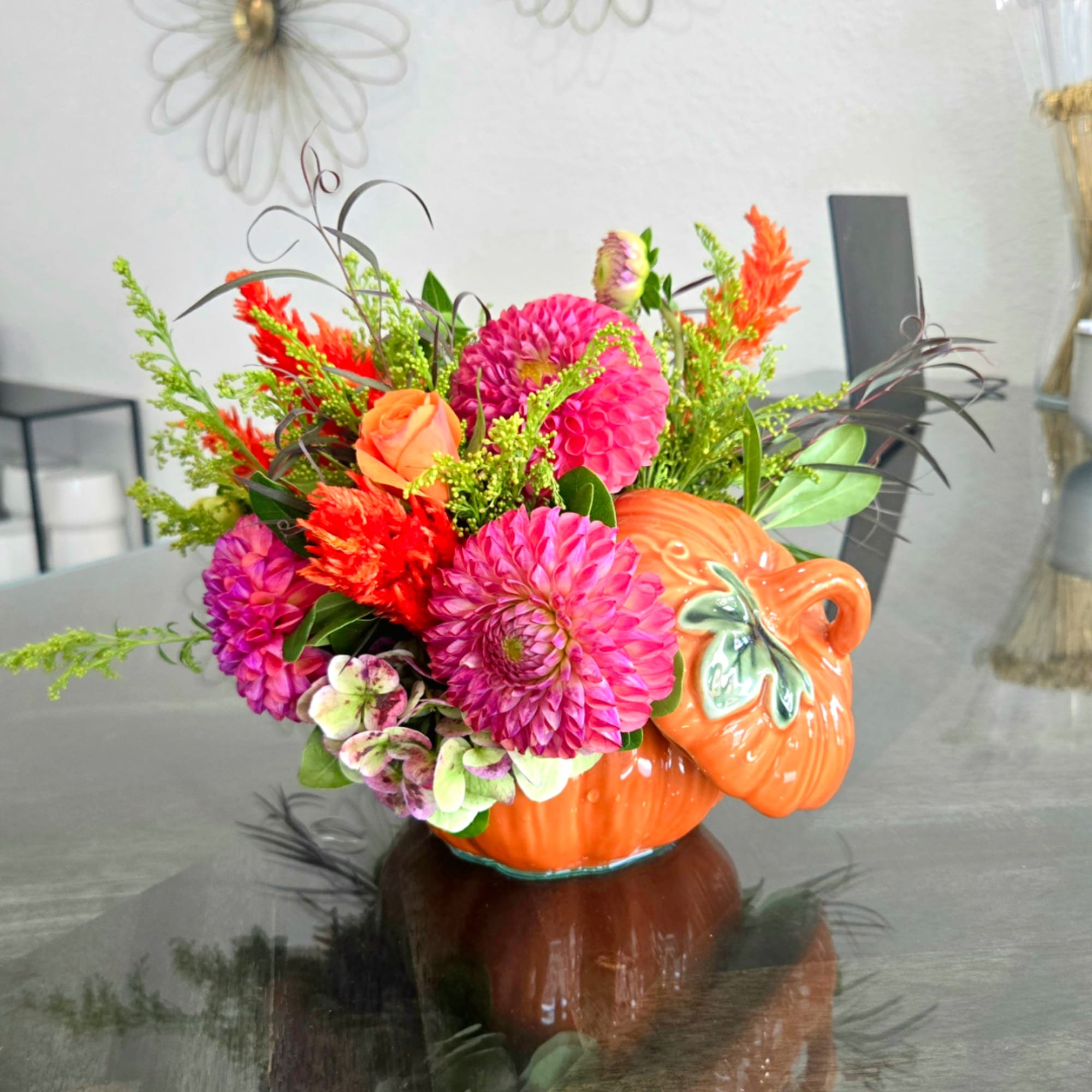 Bright mixed flower arrangement in an orange pumpkin-shaped ceramic vase