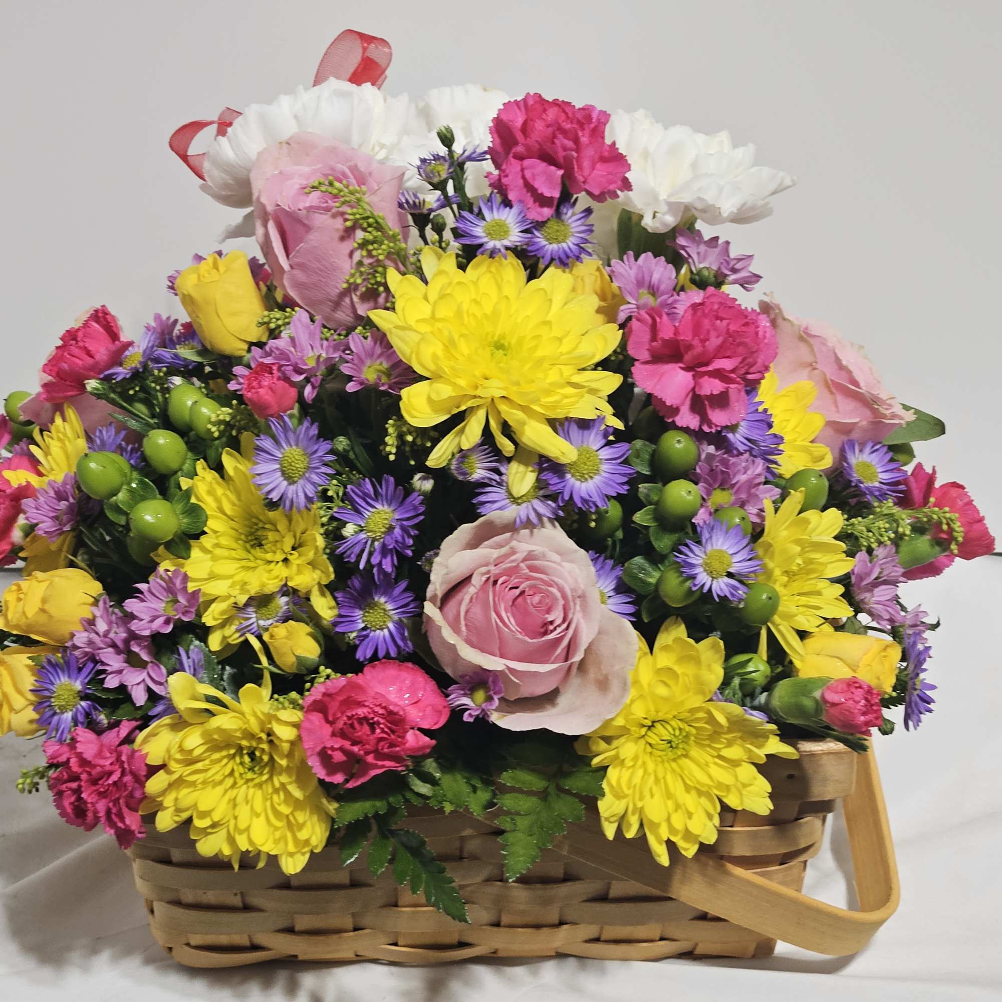 Mixed bouquet in a woven basket with pink, yellow, purple, and white flowers