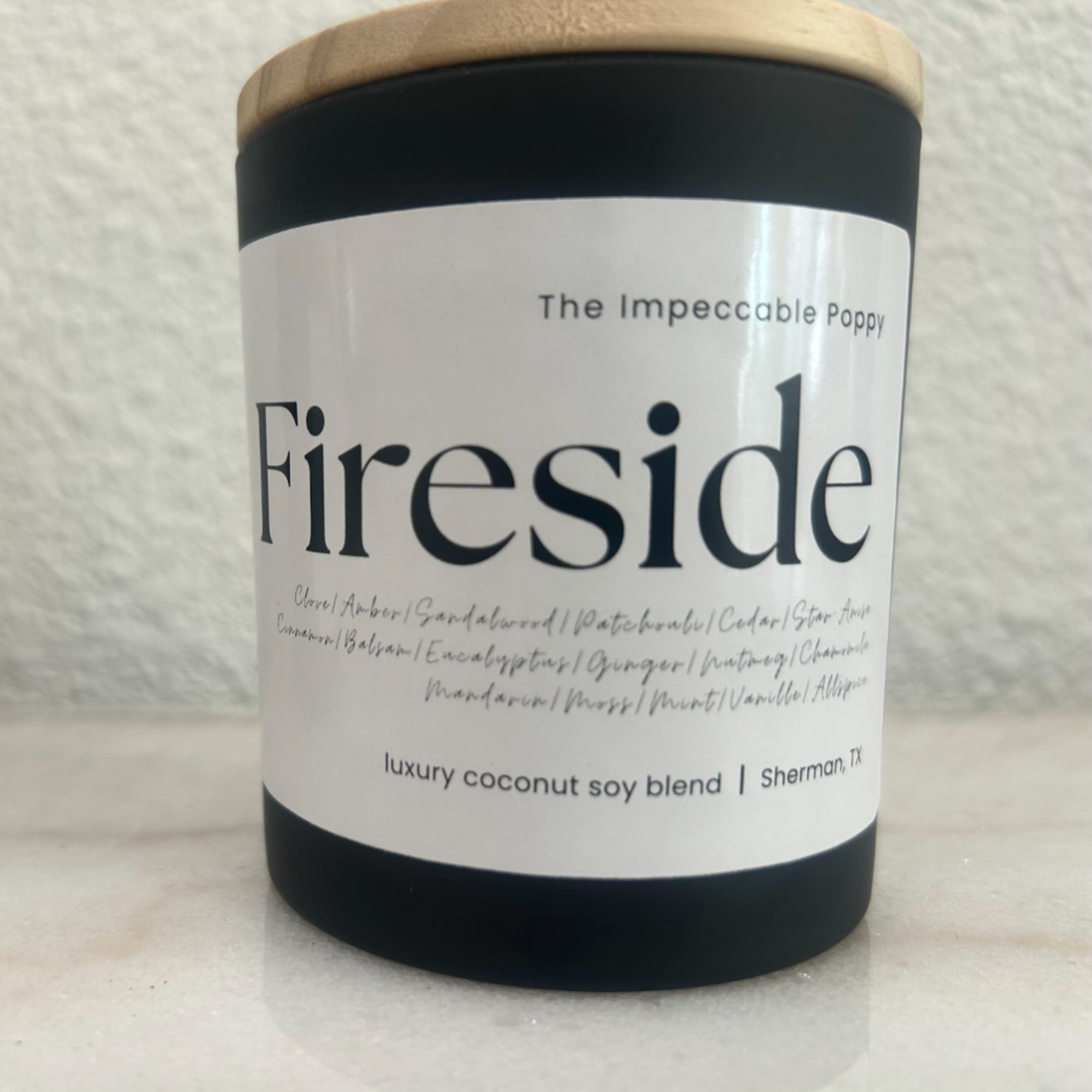 Black candle jar with a wood lid and white label reading Fireside