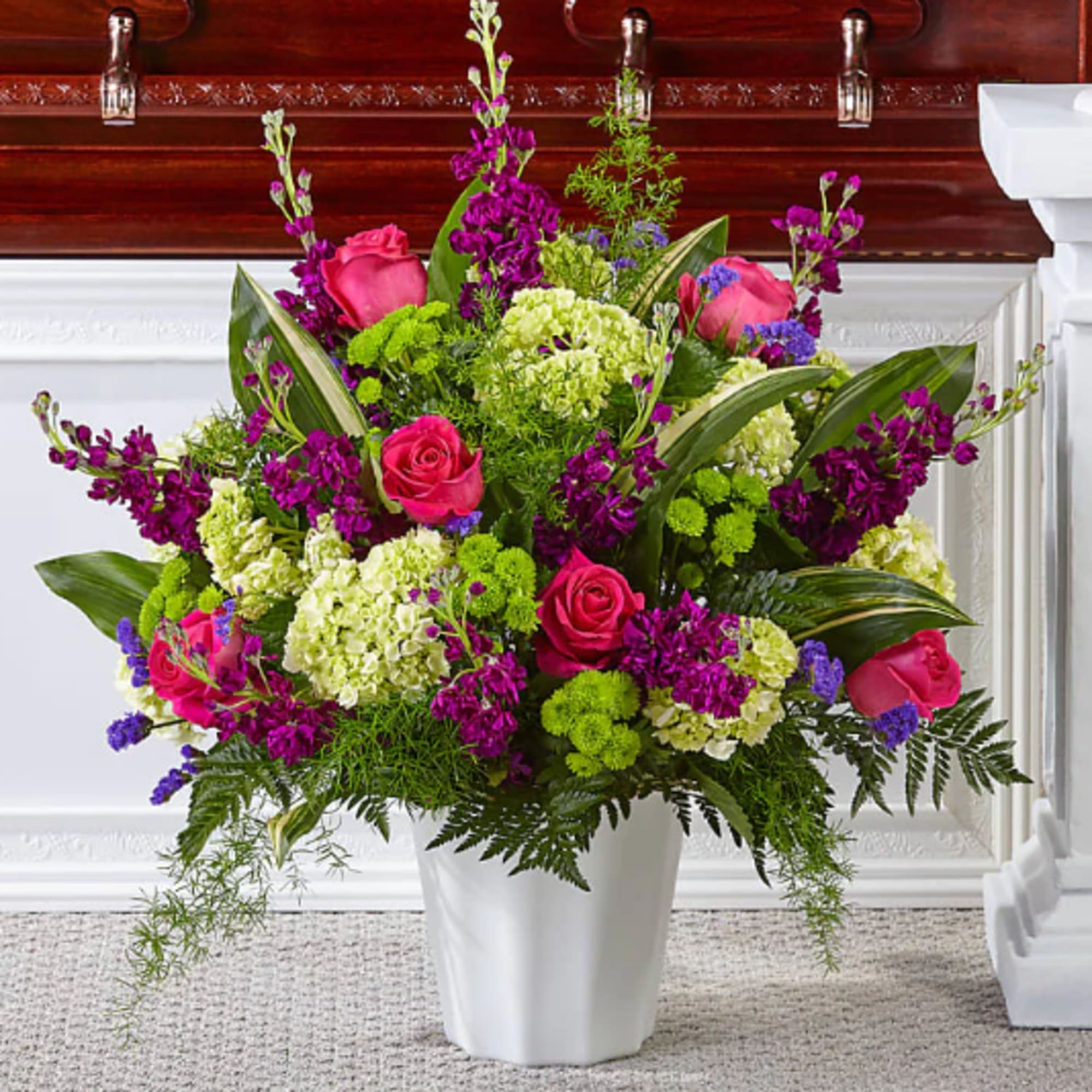 Large bouquet of pink roses and purple flowers in a white vase