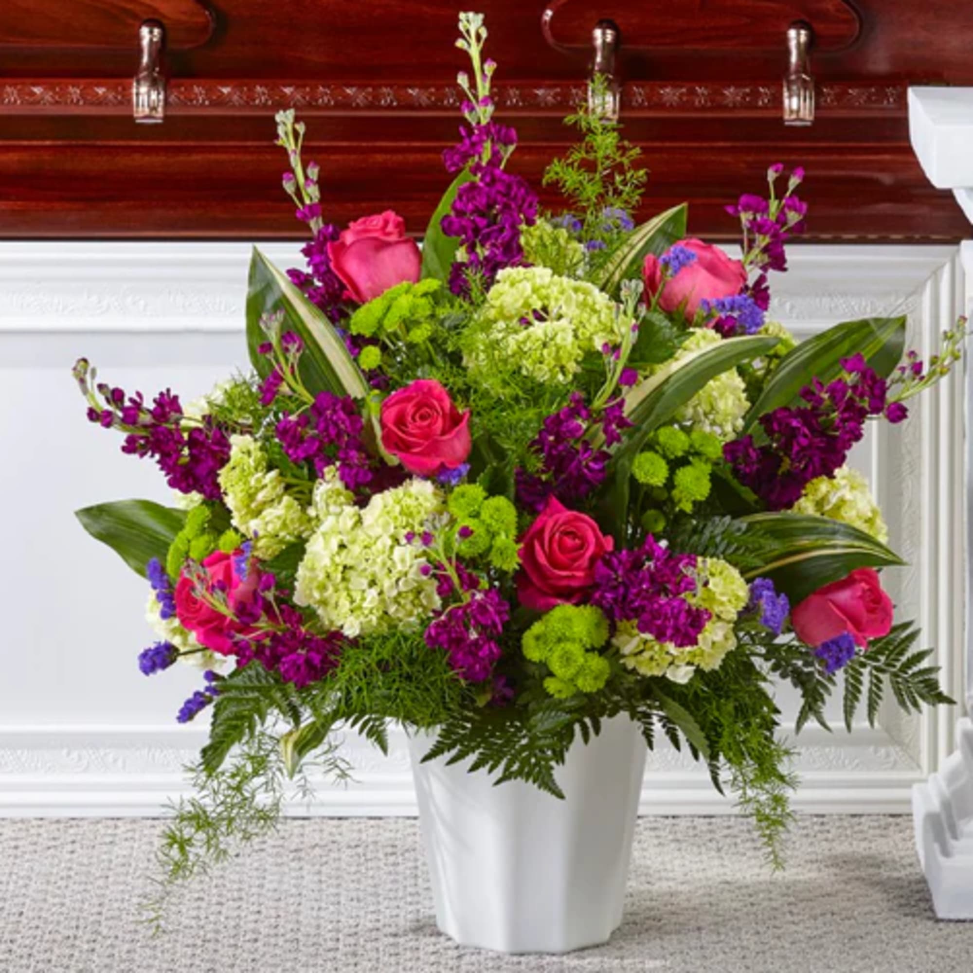 Bright mixed floral arrangement in a white vase with pink roses and purple blooms