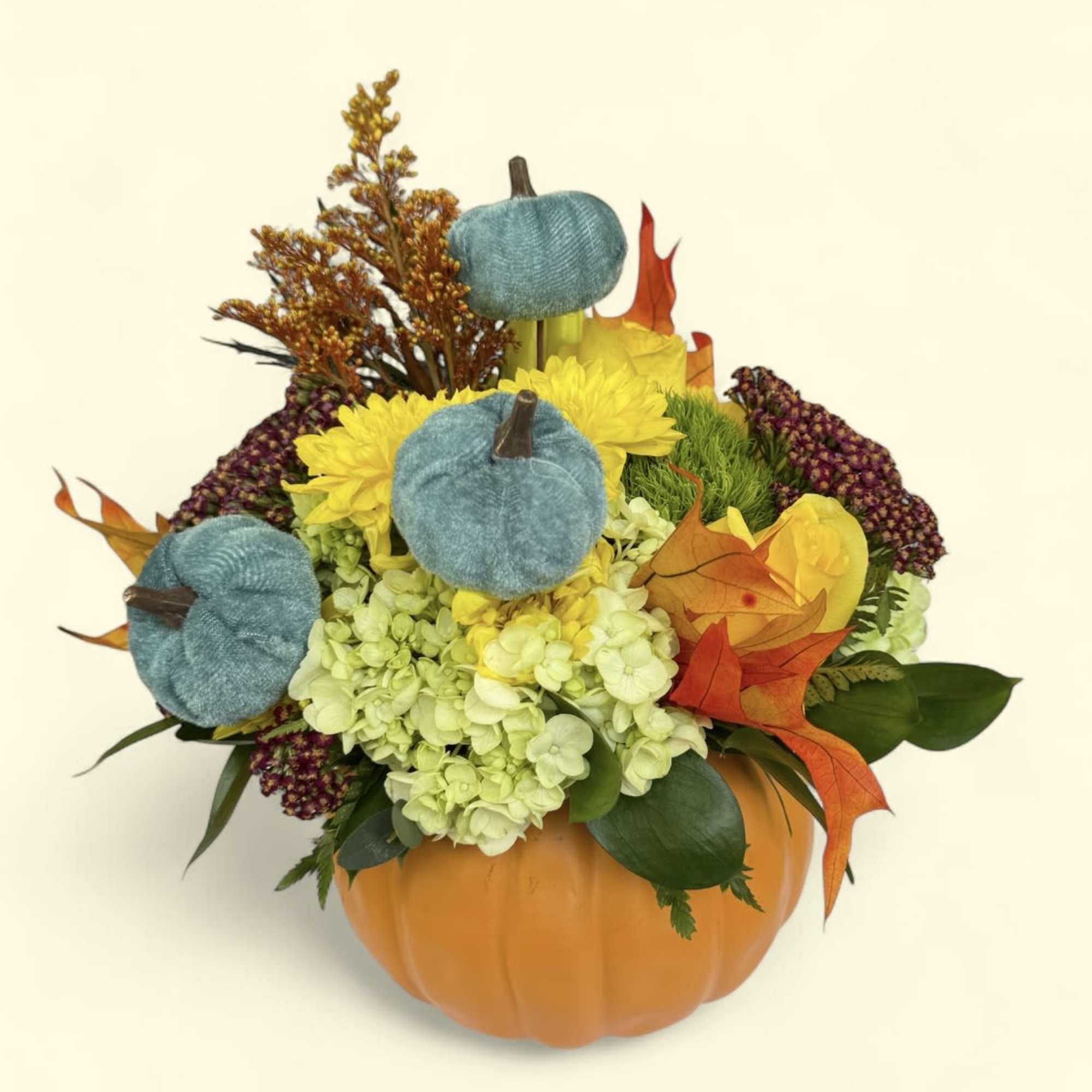 Fall floral arrangement in a pumpkin container with yellow blooms and blue pumpkins