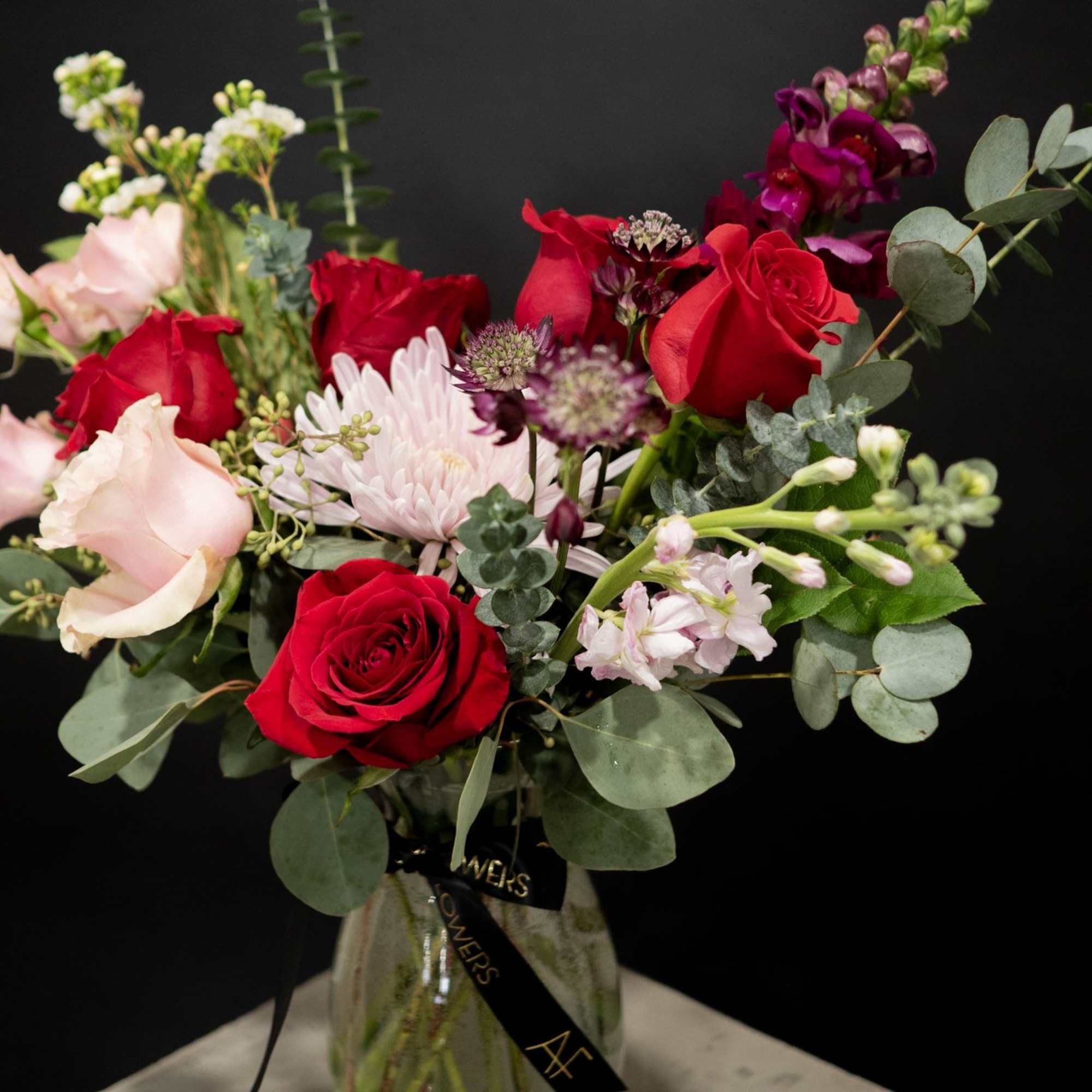 Bouquet of red and blush roses with mixed blooms in a glass vase