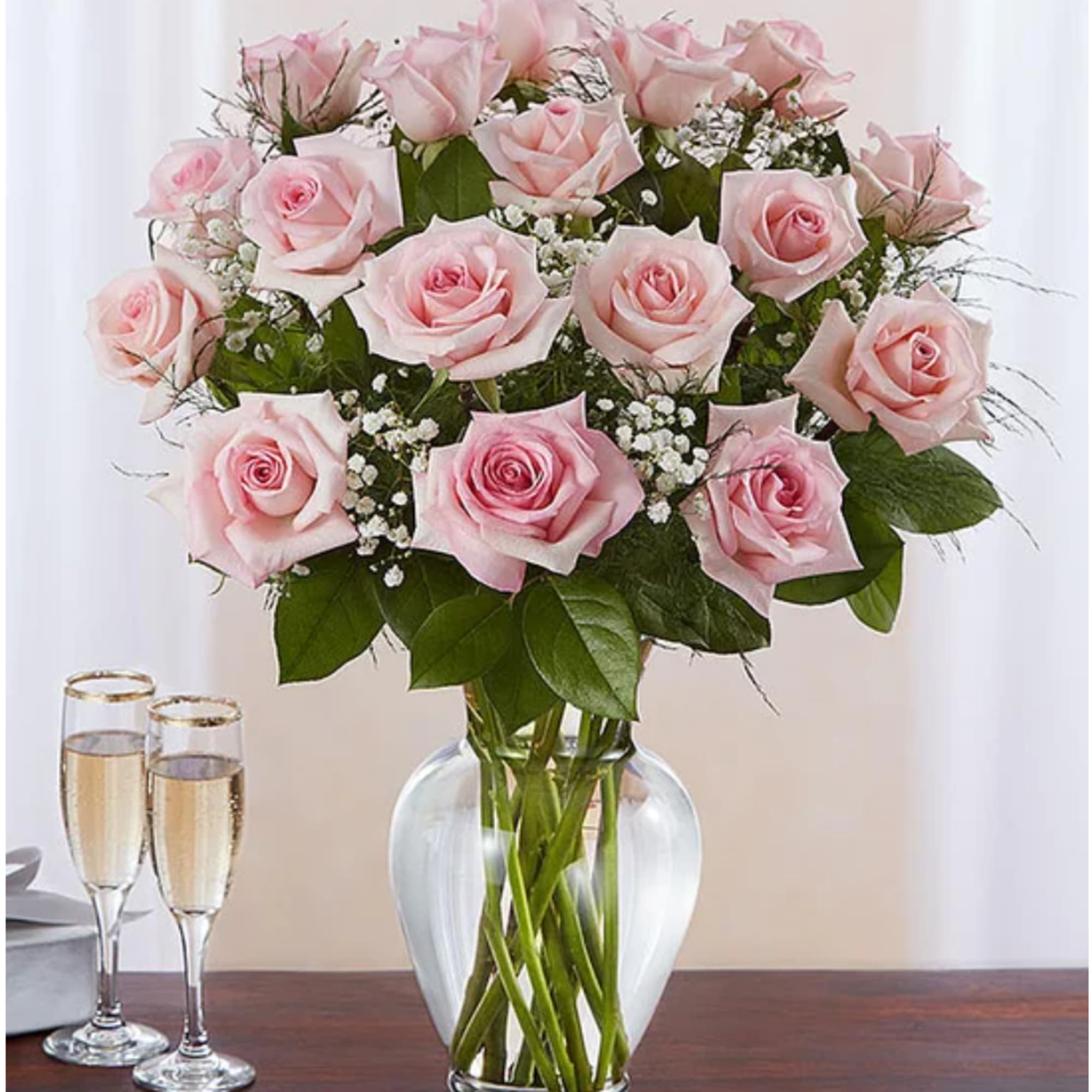Pink roses arranged in a clear glass vase with baby's breath