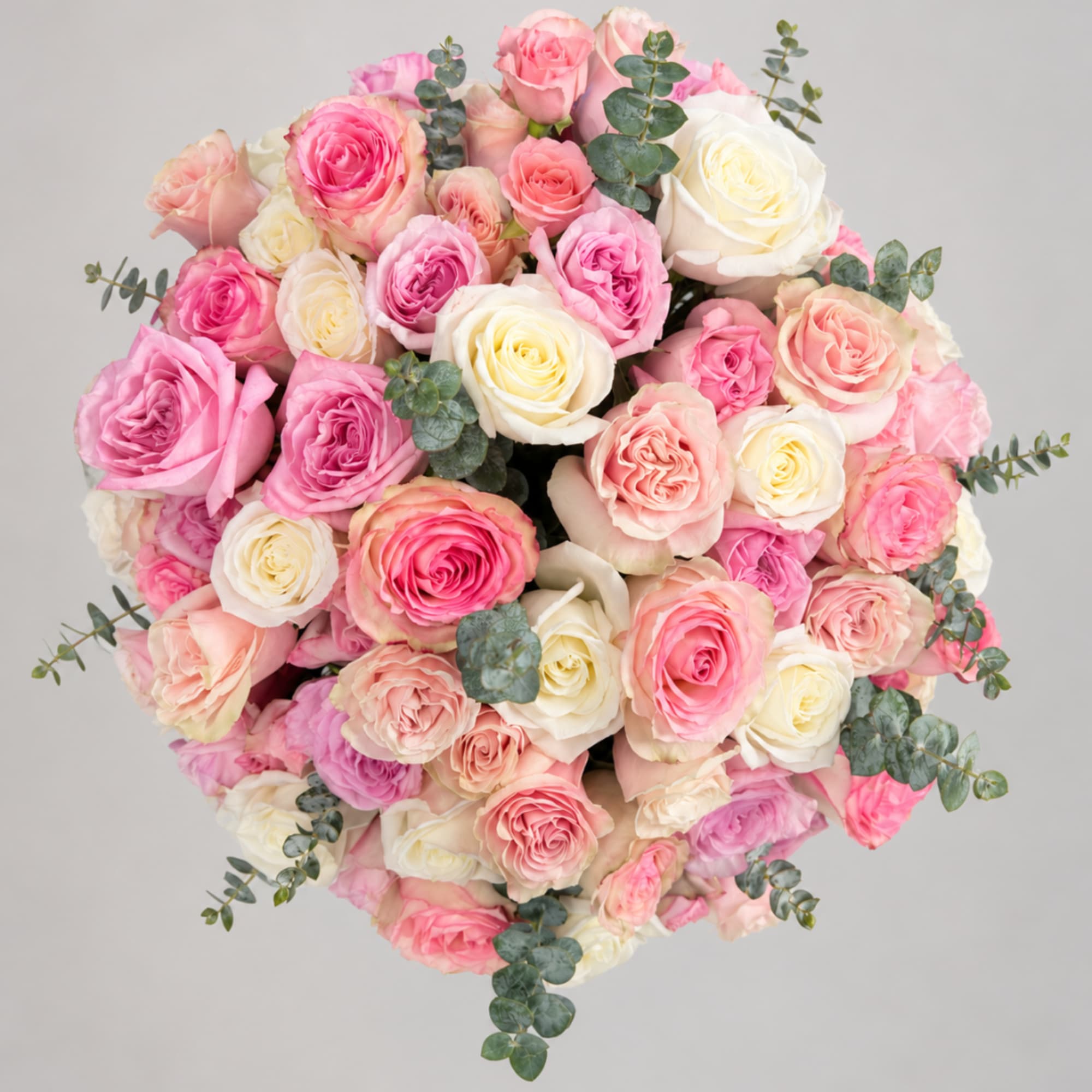 Round bouquet of pink, peach, and white roses with eucalyptus accents