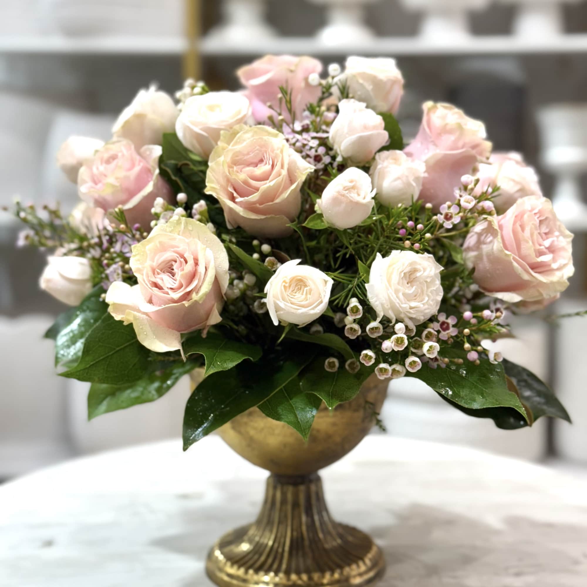 Pink and white roses arranged in a gold pedestal vase